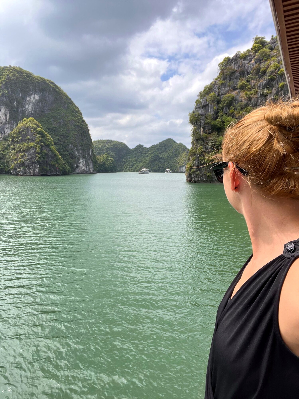 Andreja looking across calm green water between limestone cliffs in Lan Ha Bay