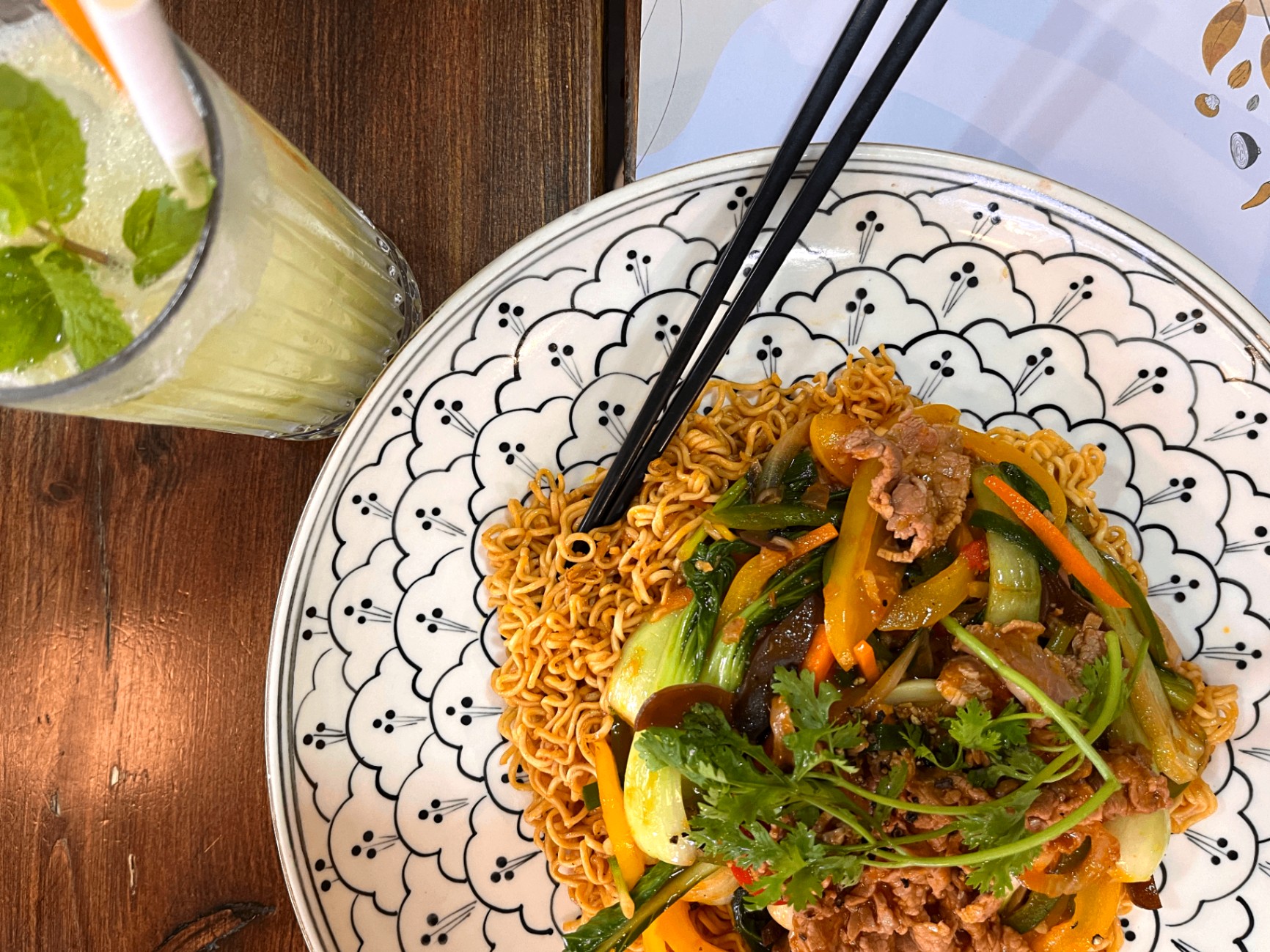 Fried noodles with beef and vegetables on a patterned plate in Hanoi