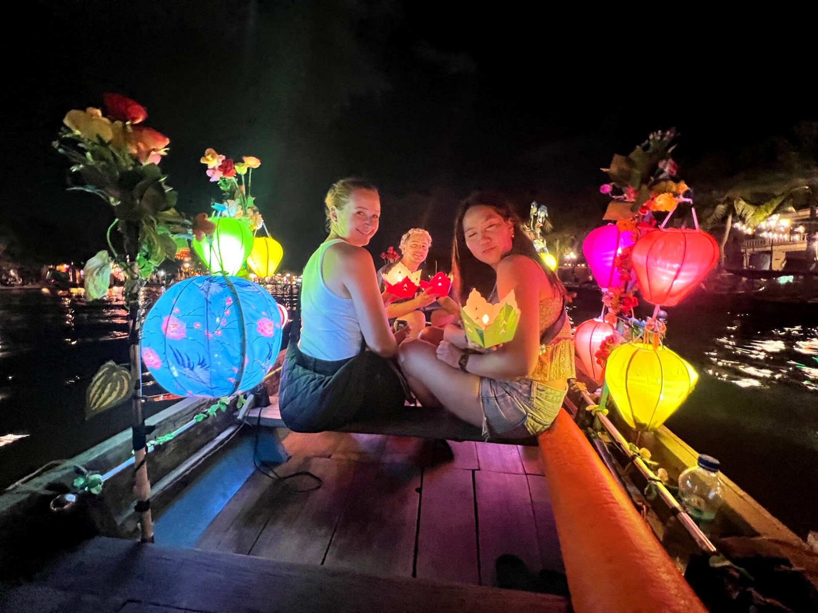 Andreja and friends on a Hoi An river boat surrounded by glowing lanterns