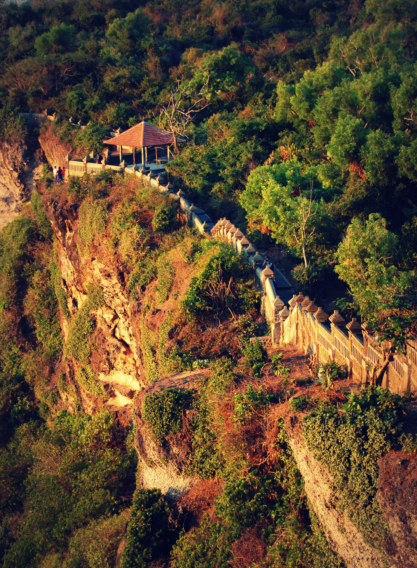A small tiled pavilion and stone walkway along the Uluwatu clifftop temple path