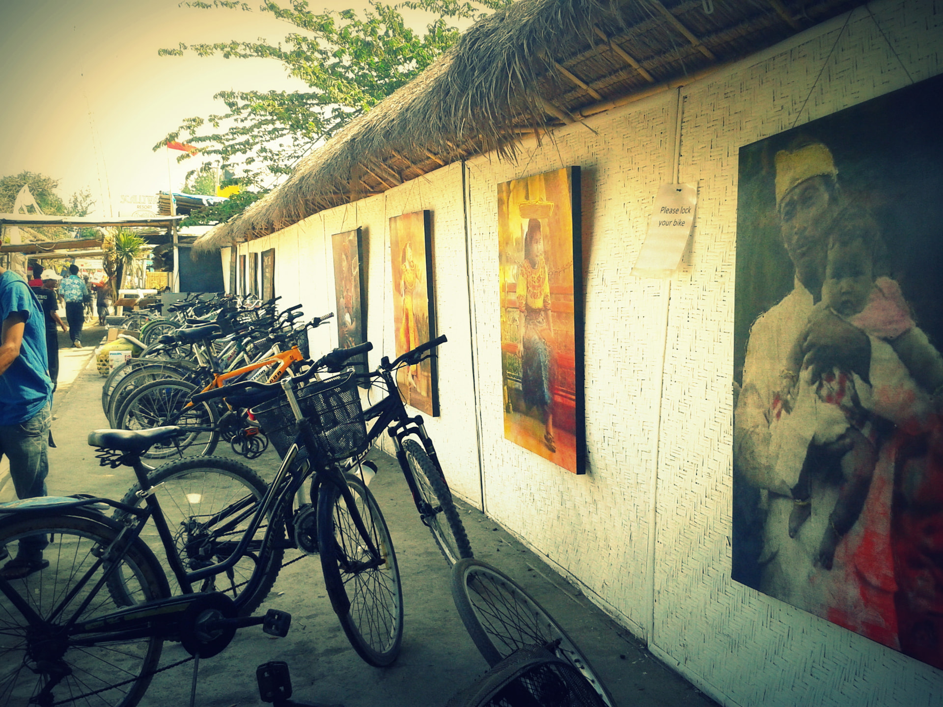 Rental bicycles parked along a thatched wall on a sandy Gili Trawangan street