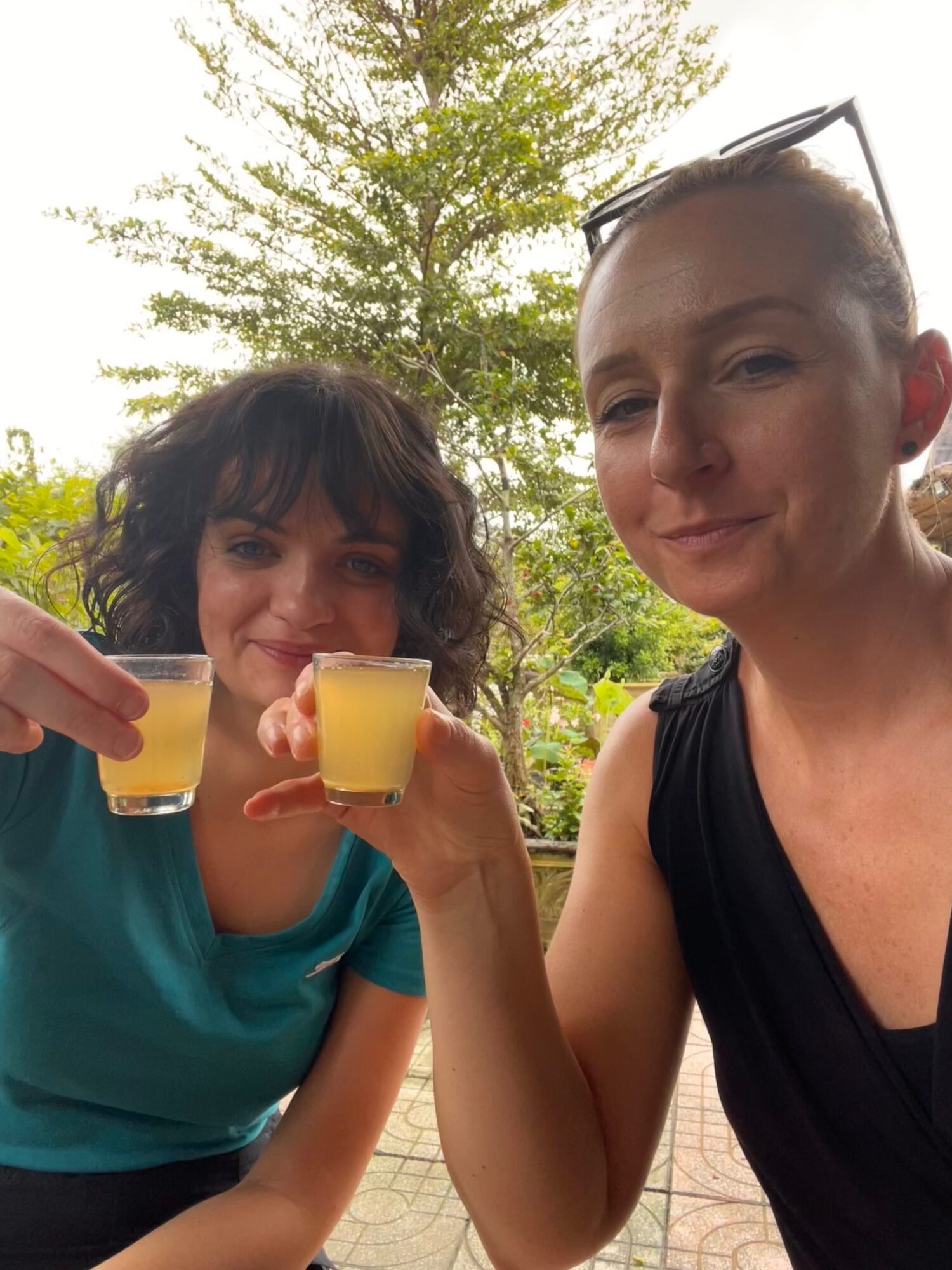 Two travellers holding small cups of honey drink during the Mekong Delta tour