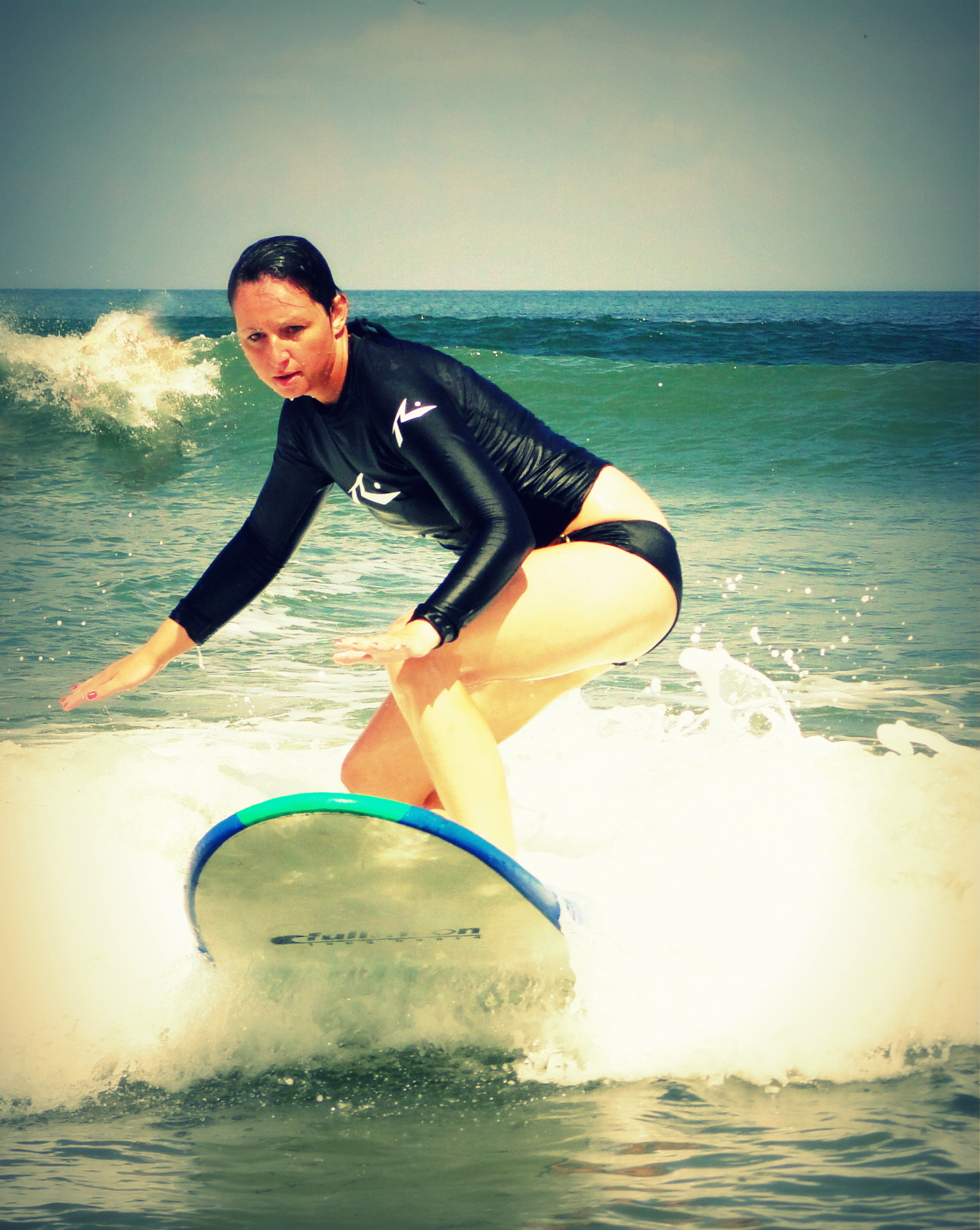 Surfing a small wave on a beginner board at Kuta Beach, Bali
