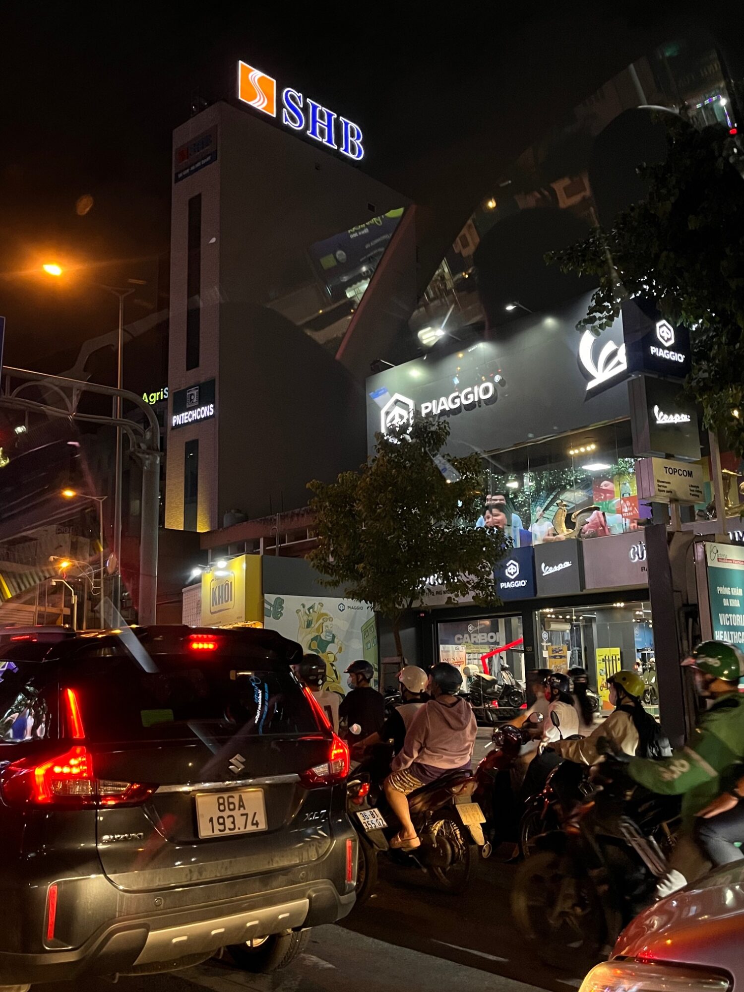 Rainy Saigon street at night with taxis, scooters and bright storefronts