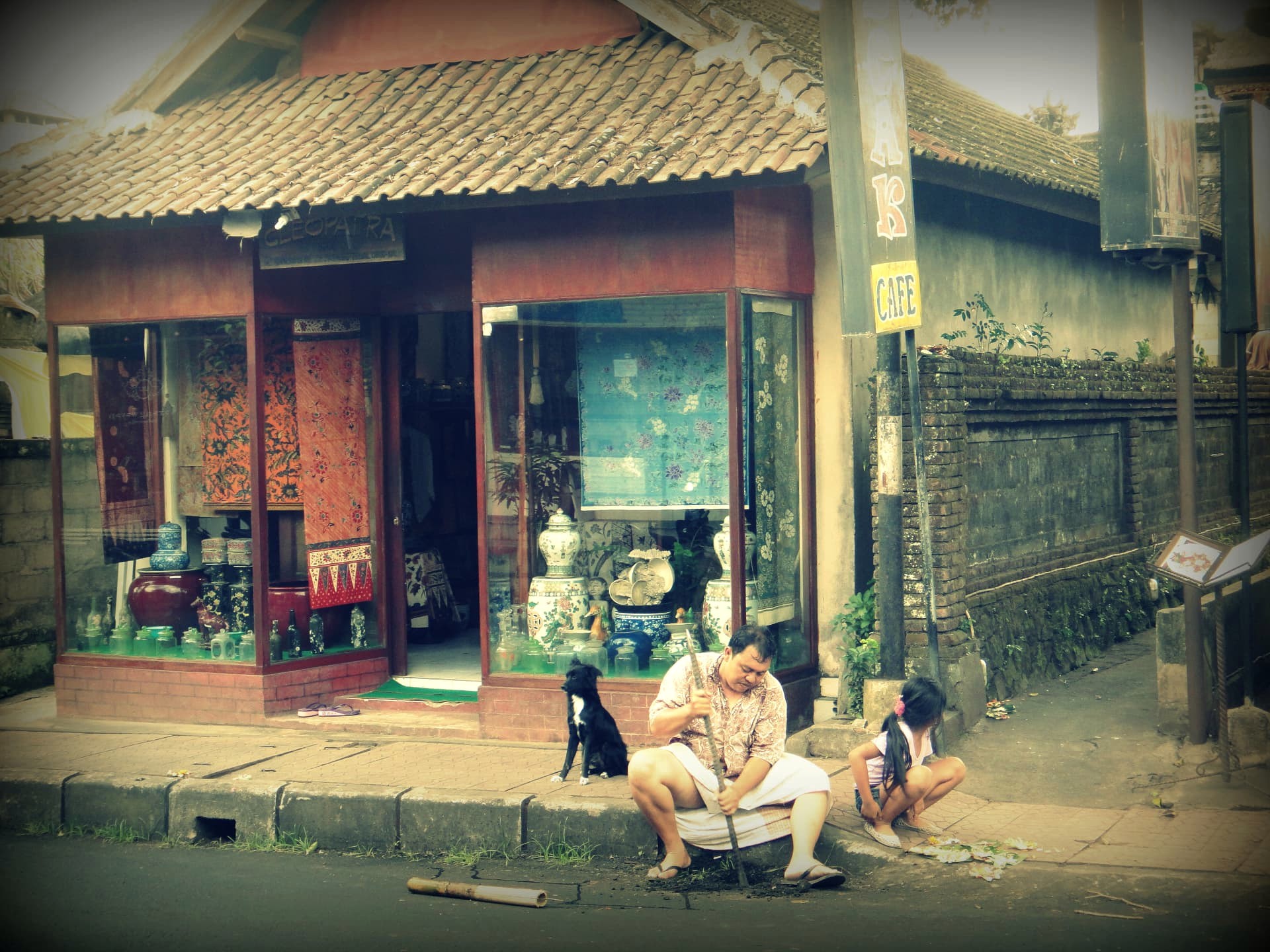 A family and dog outside a small craft shop on an Ubud street