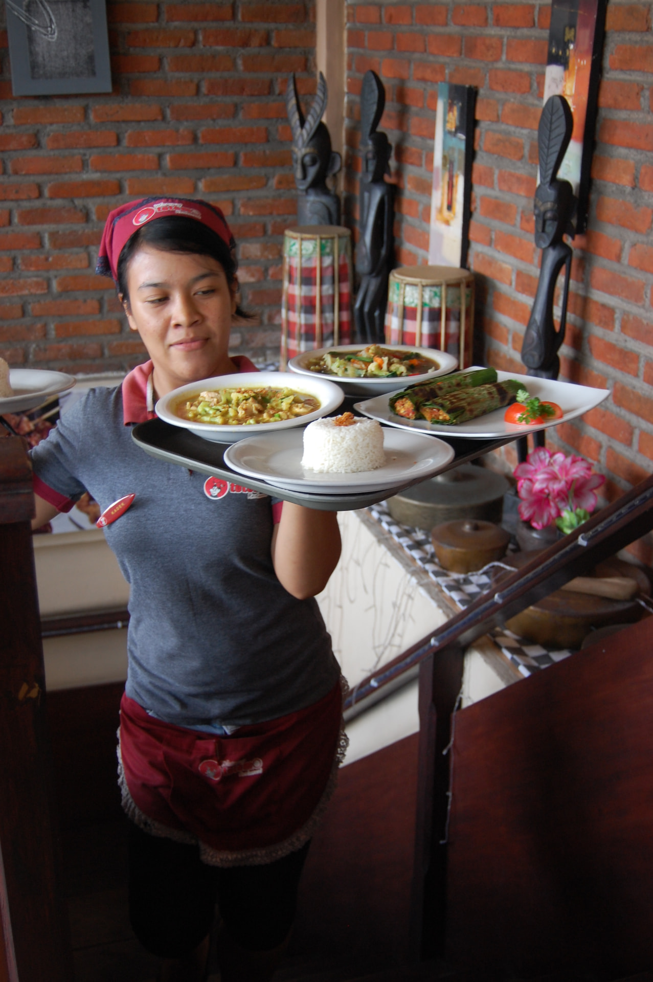 A waitress carrying a tray of Balinese curries, rice and banana-leaf dishes at a restaurant in Kuta
