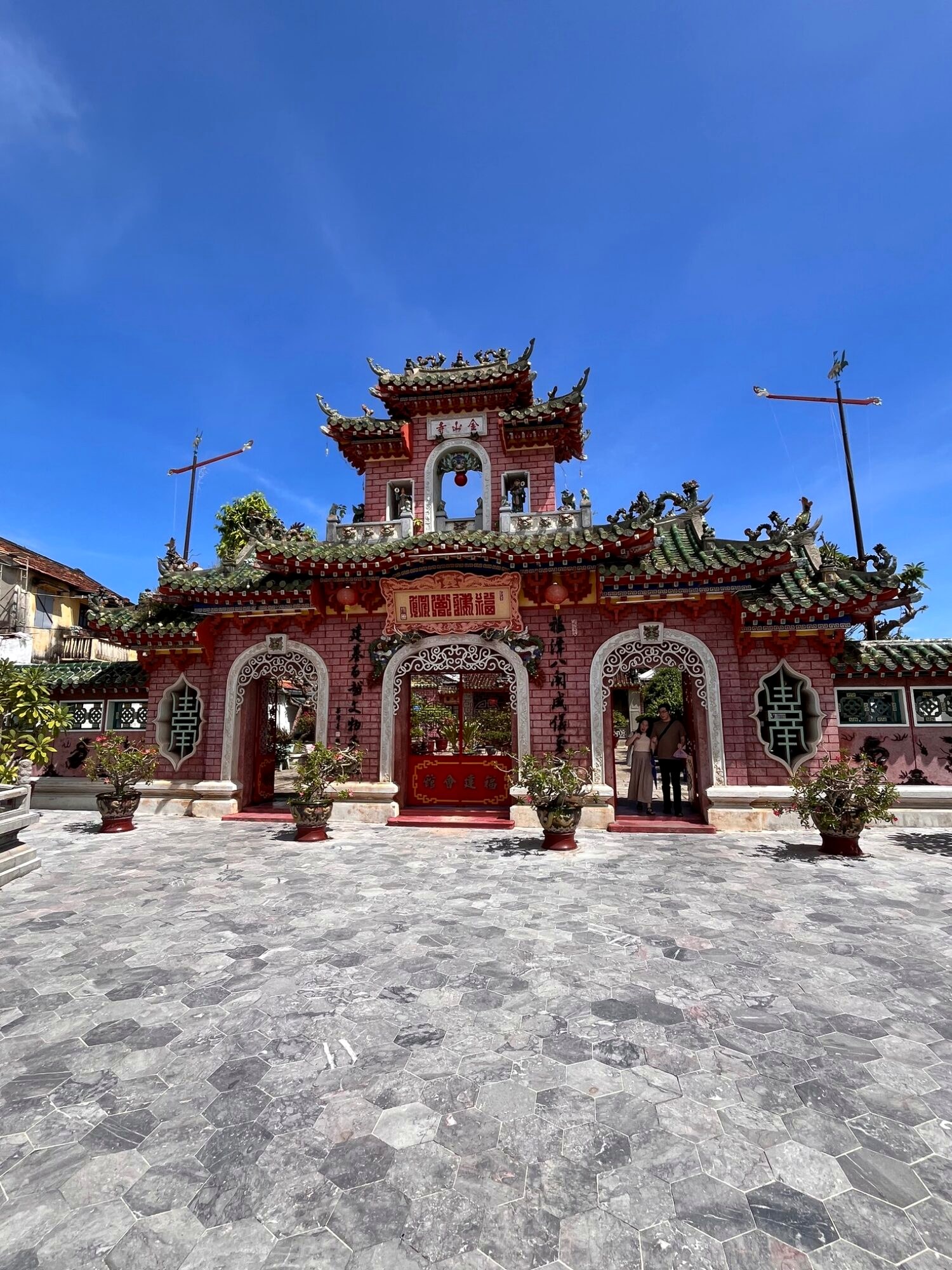 The colourful tiled gate of the Fujian Assembly Hall in Hoi An under a blue sky