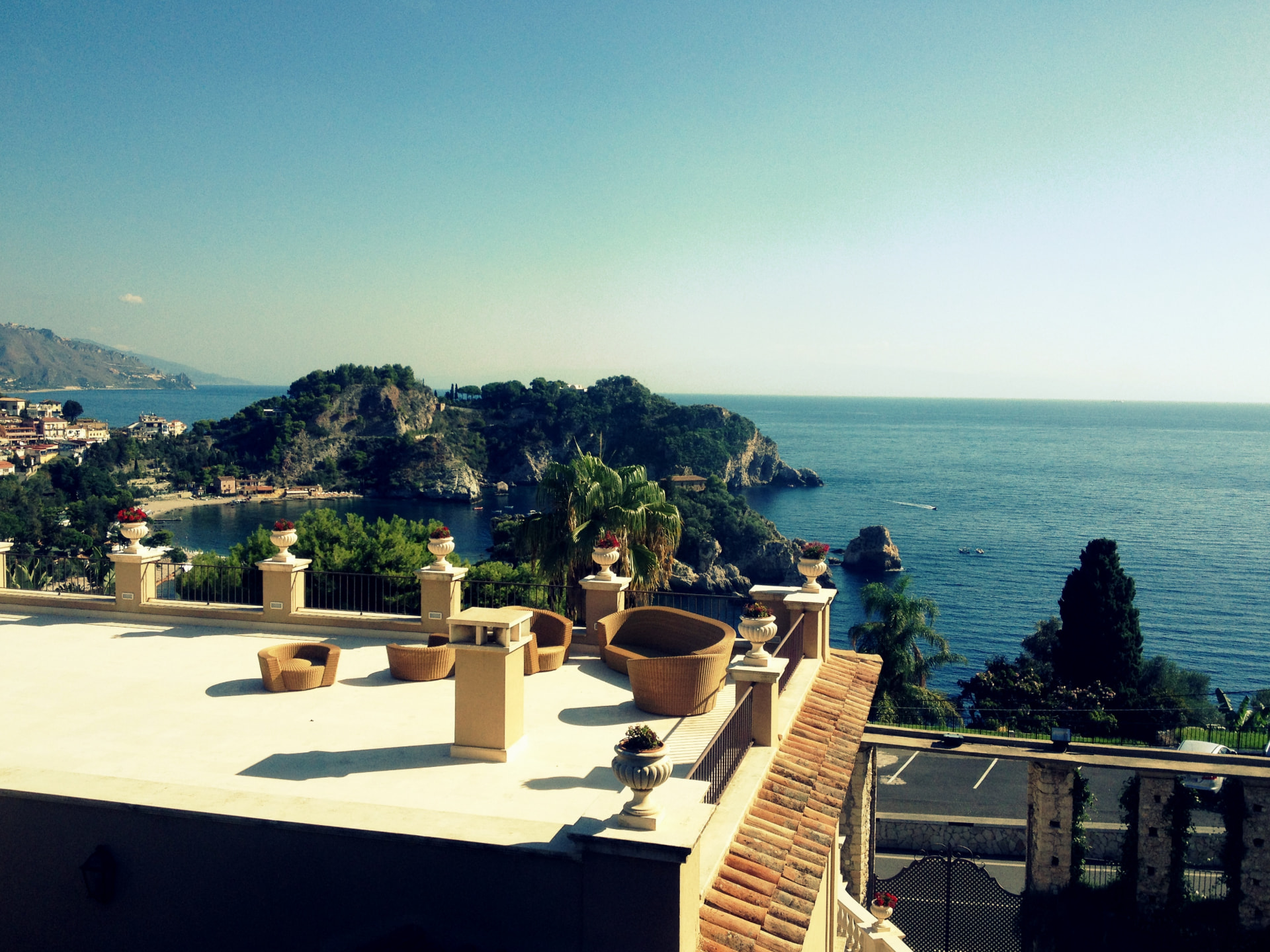 A wicker chair on a Taormina terrace overlooking Isola Bella and the blue sea