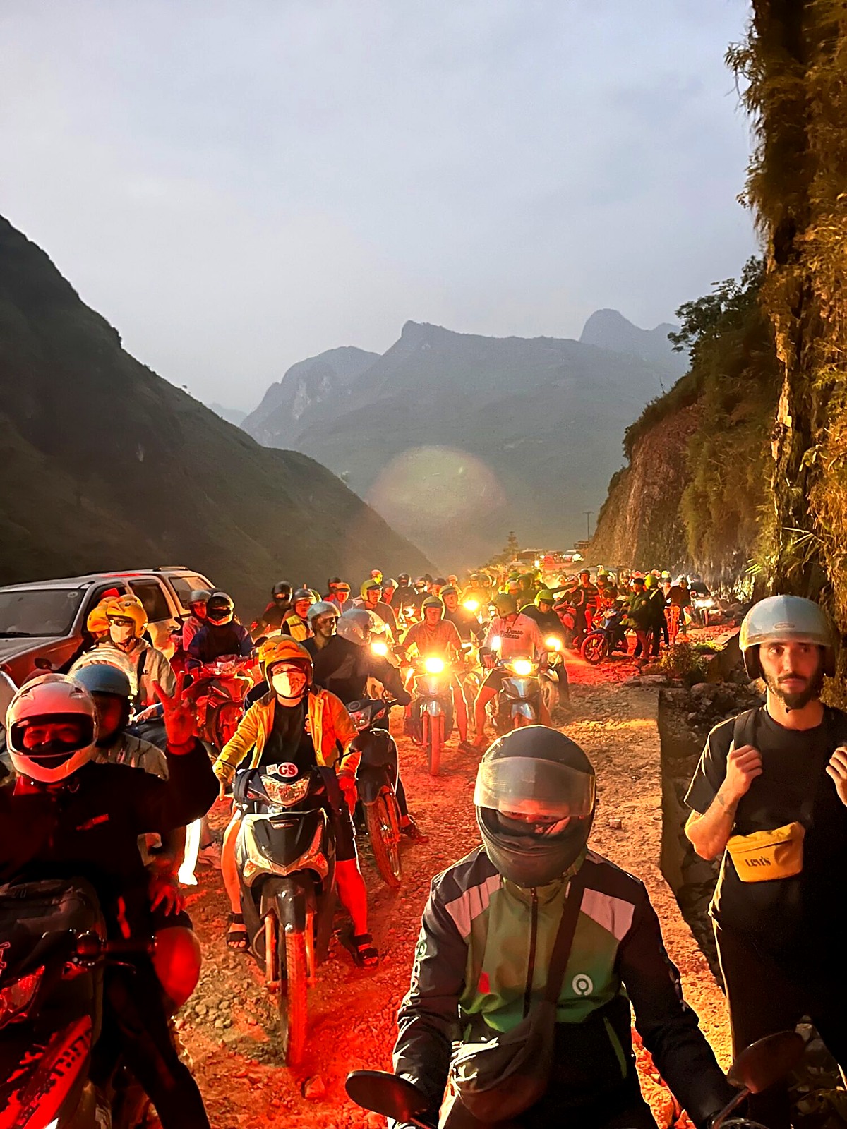 Motorbike riders lined up on a mountain road as darkness falls