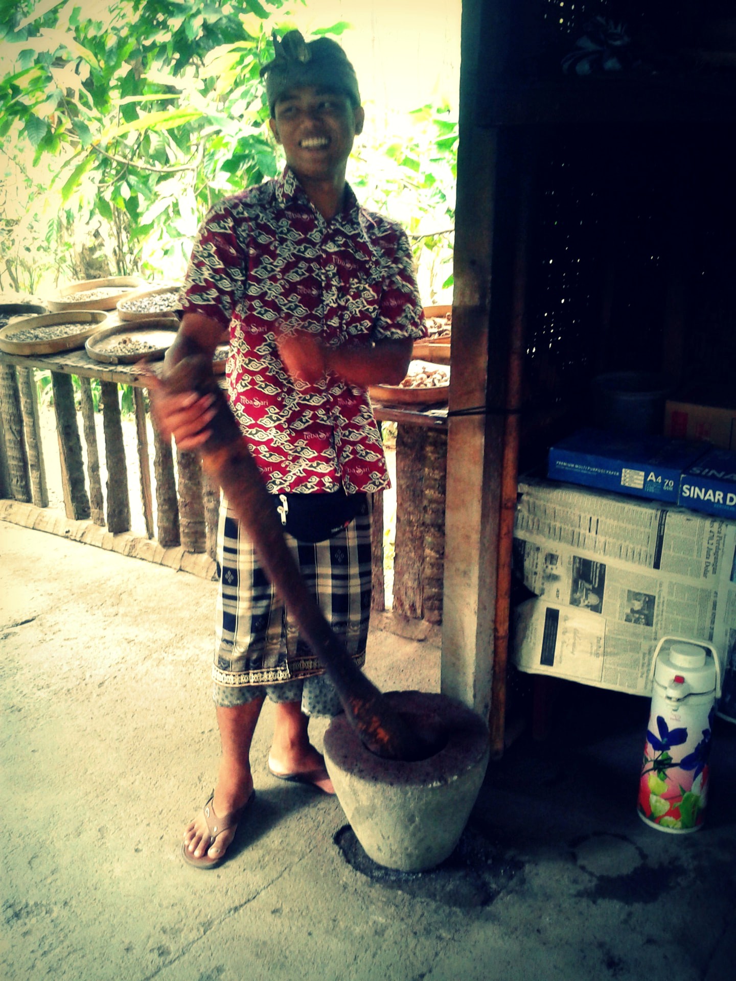 A man crushing roasted kopi luwak coffee beans by hand in a stone mortar