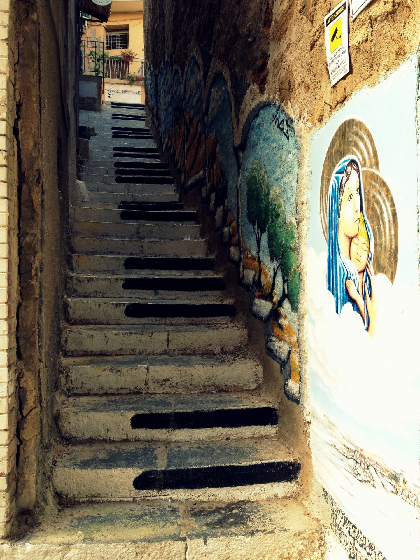 Stone steps in Agrigento painted to look like piano keys, beside a painted mural