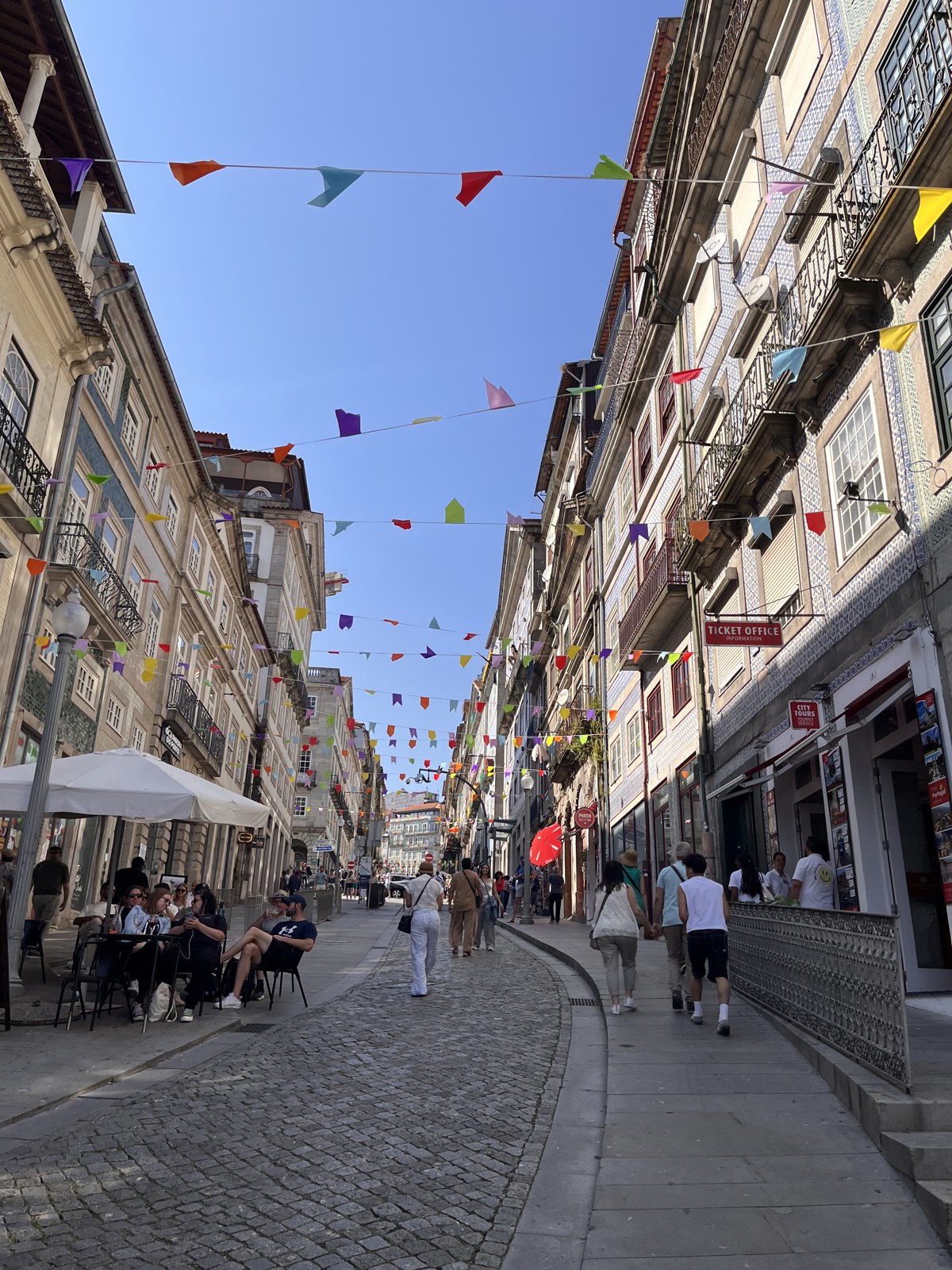 A Porto street strung with colourful festival flags and café tables on the cobbles