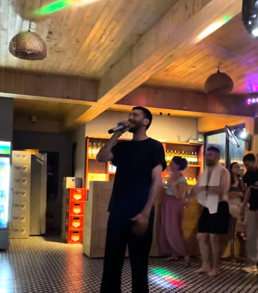 A man singing into a microphone during a lively karaoke evening