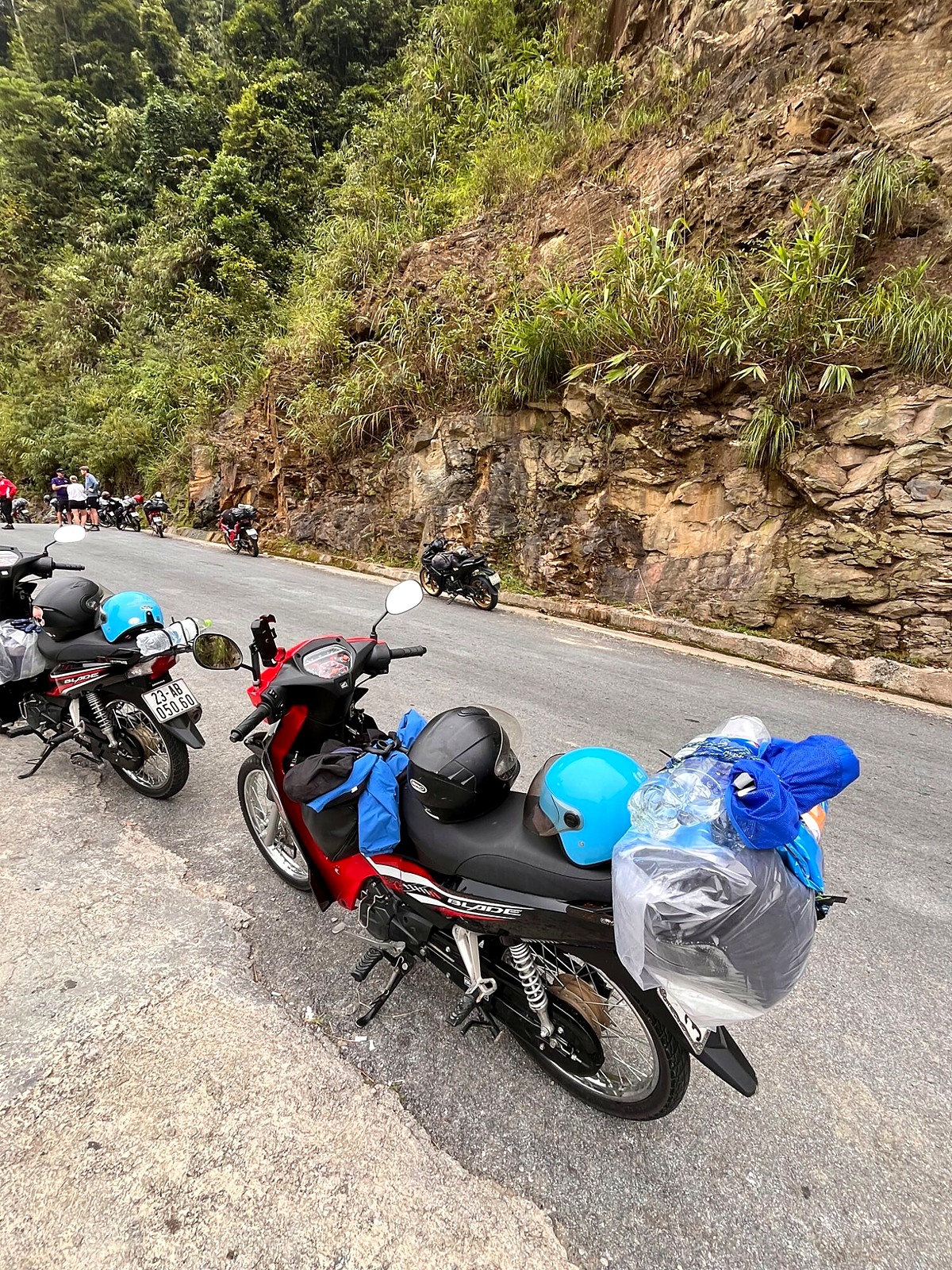 Tour motorbikes parked beside a rocky mountain road with luggage strapped on