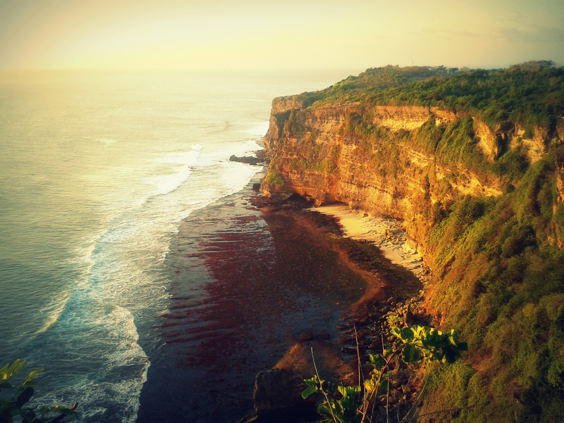 Golden evening light on the limestone cliffs and surf below Uluwatu, Bali