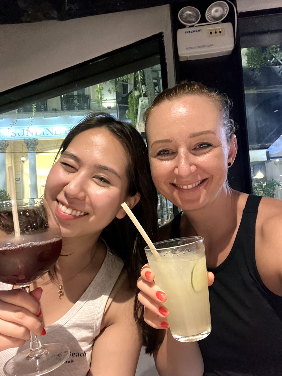 Two friends raising drinks together in Hanoi