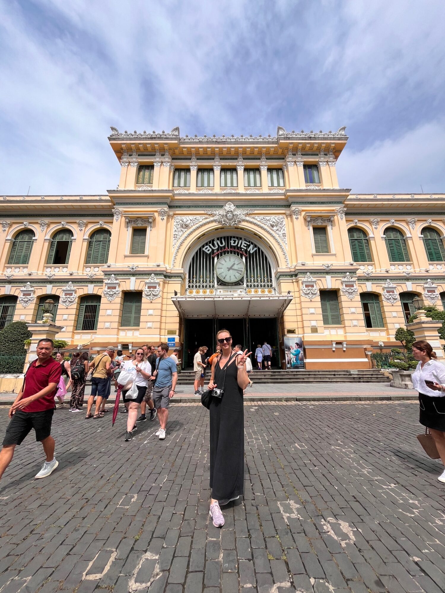 Yellow French-colonial facade of Saigon Central Post Office with visitors outside