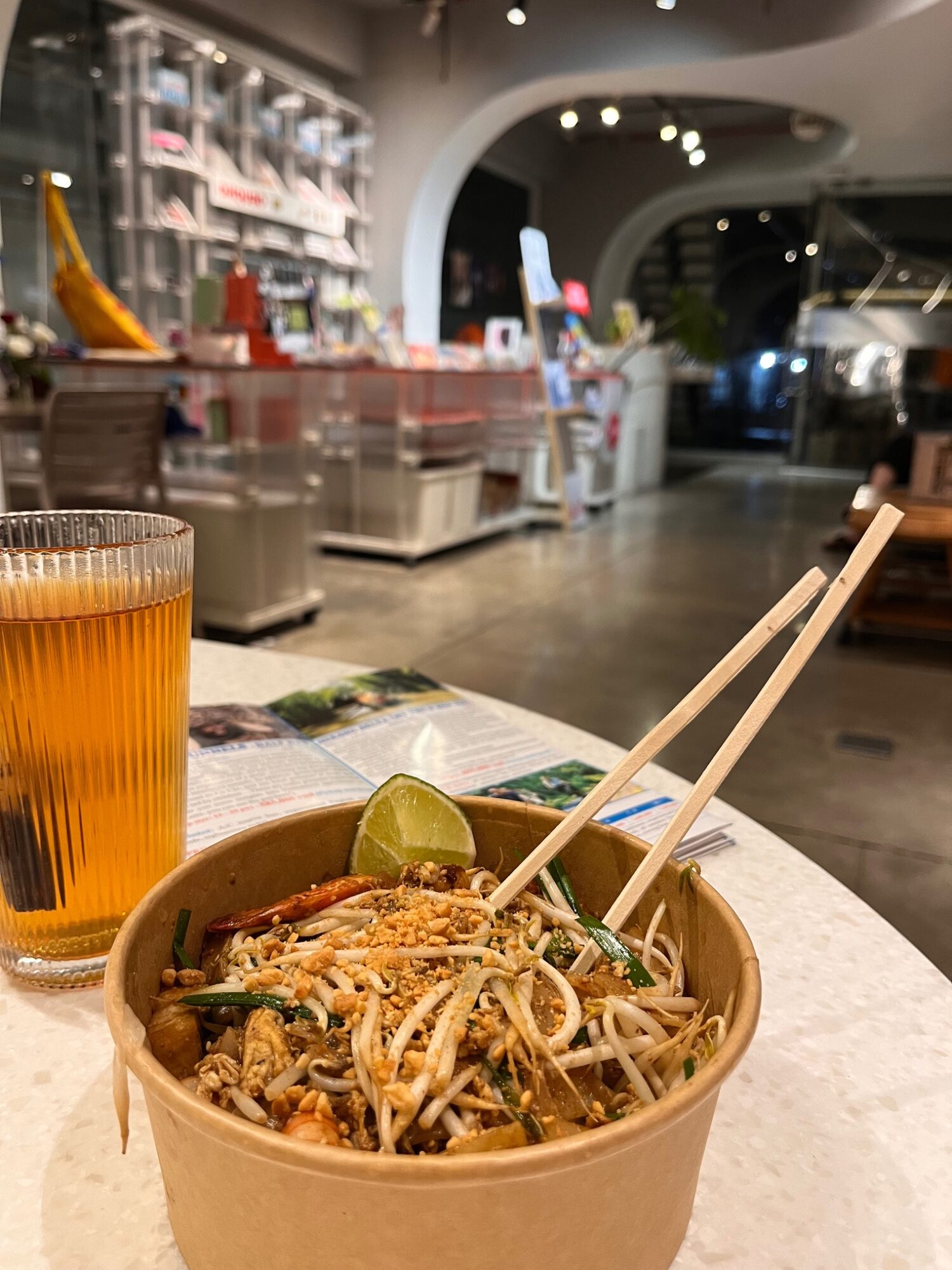 Bowl of noodles with chopsticks and a drink on a restaurant counter