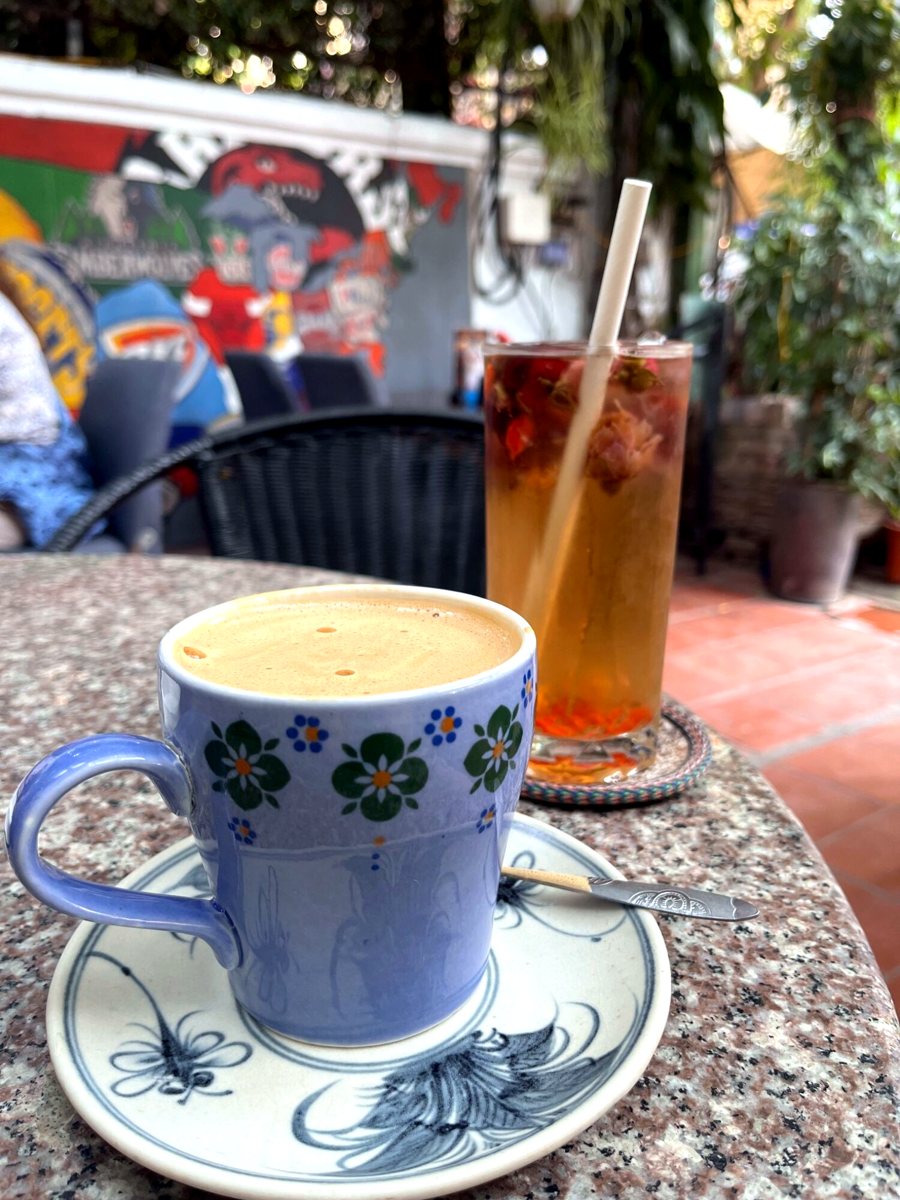 Egg coffee in a floral cup next to an iced tea in a Hanoi café