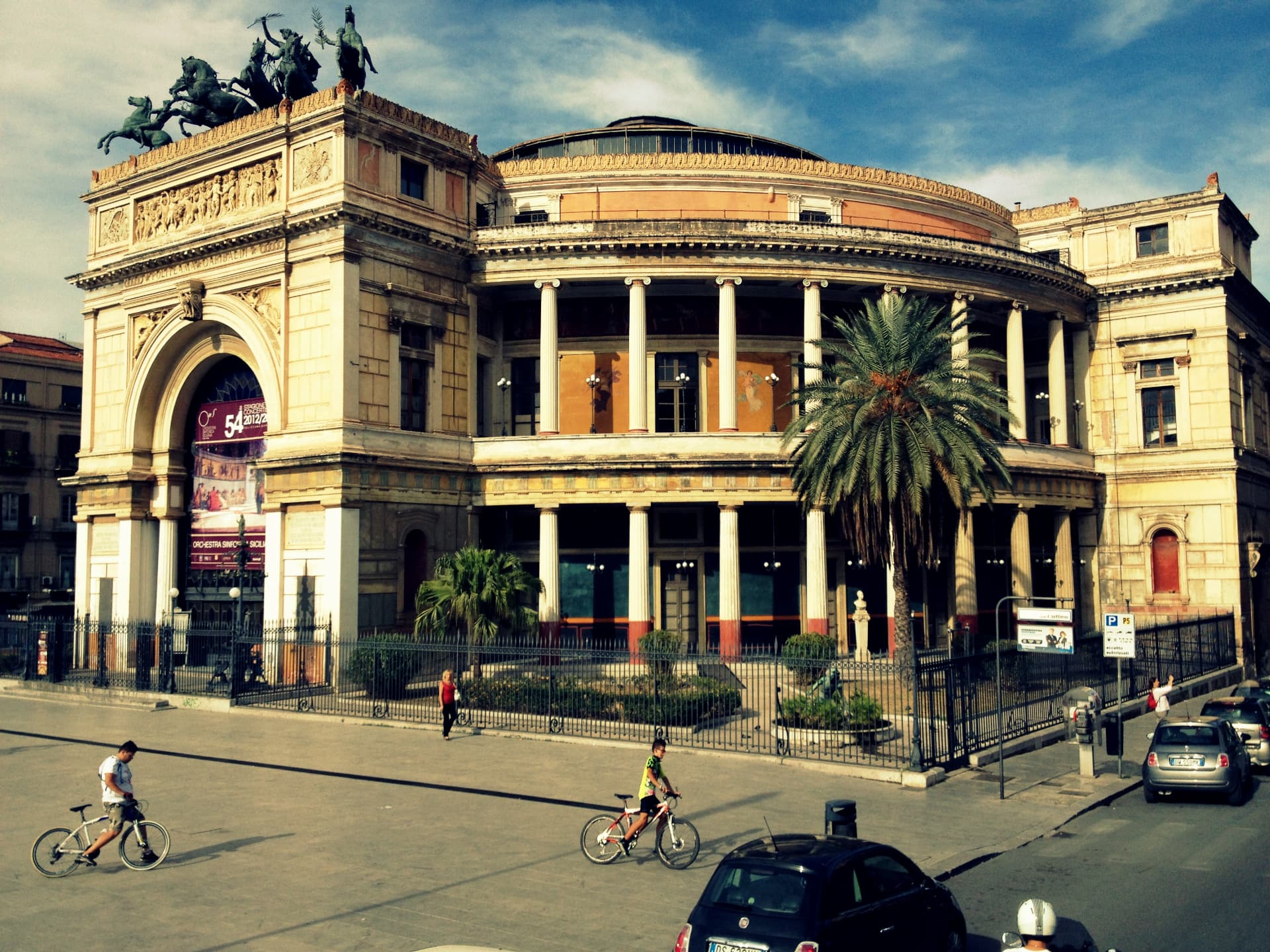 The Teatro Politeama Garibaldi in Palermo with cyclists passing in front of it