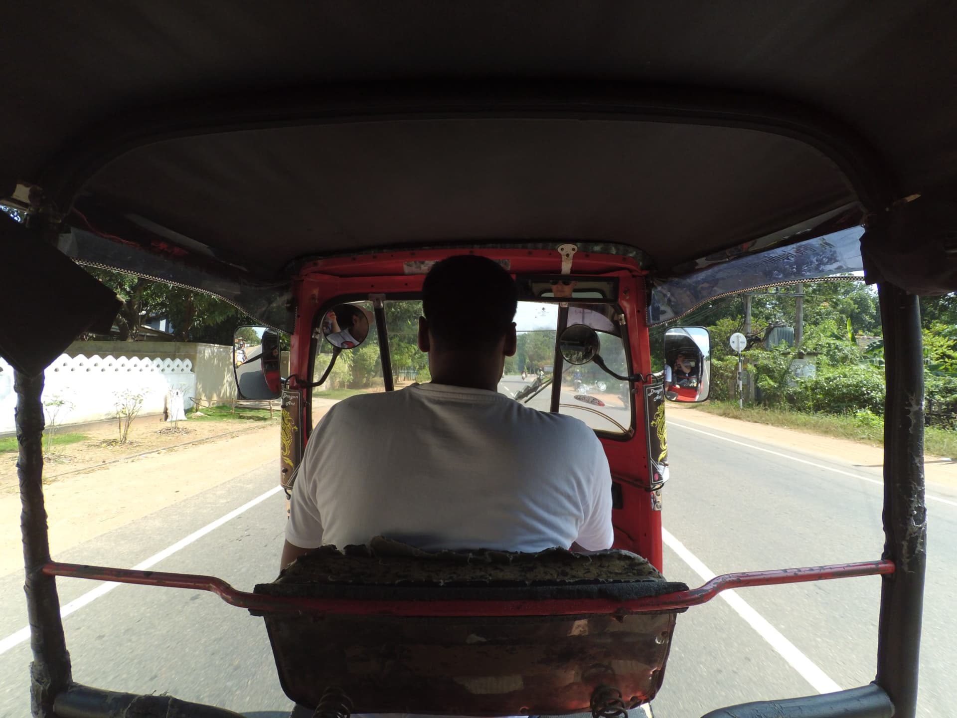 View from the back seat of a tuk-tuk driving down a Sri Lankan road