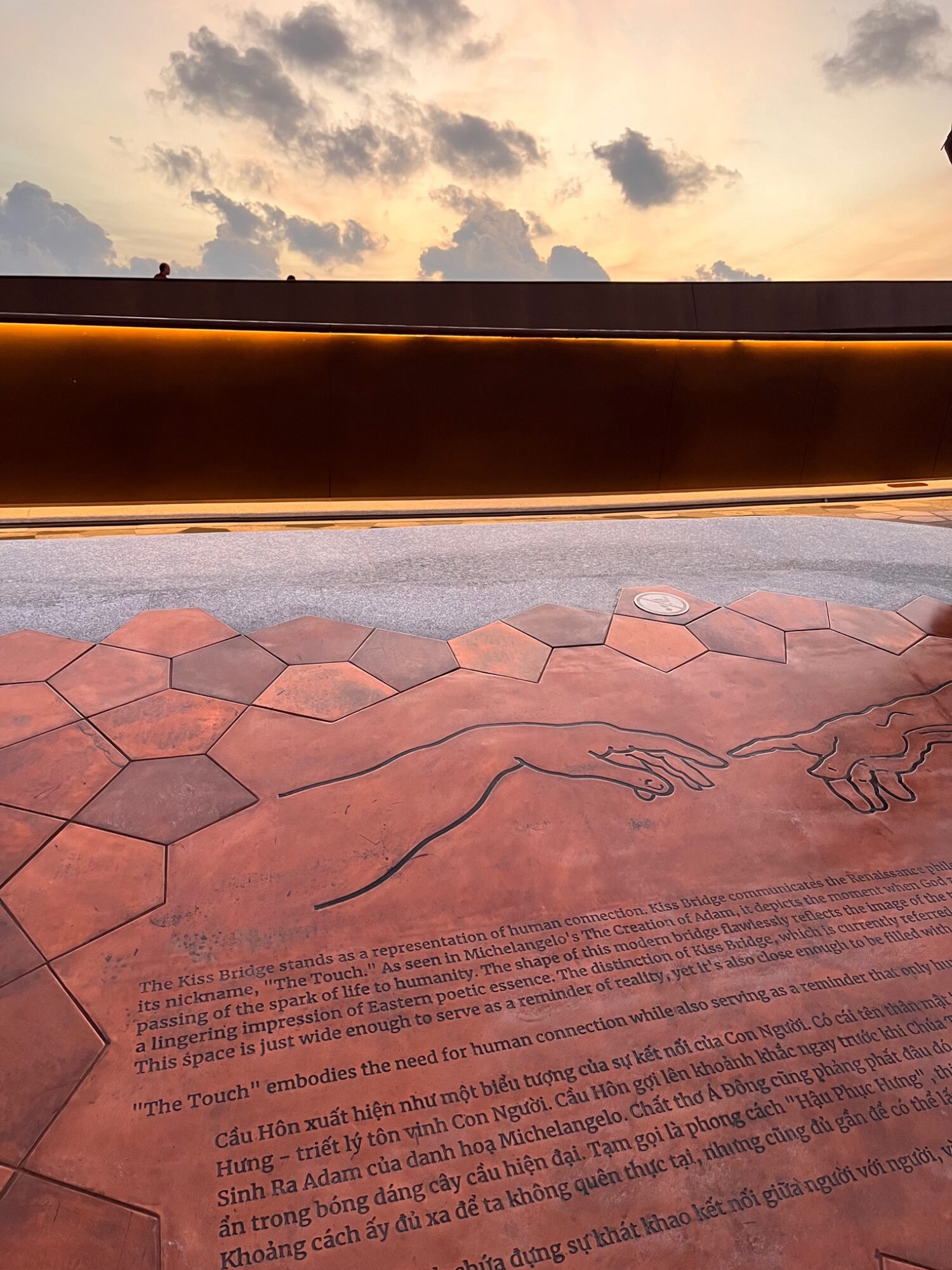 Golden sunset behind the Kiss Bridge with a patterned promenade in front