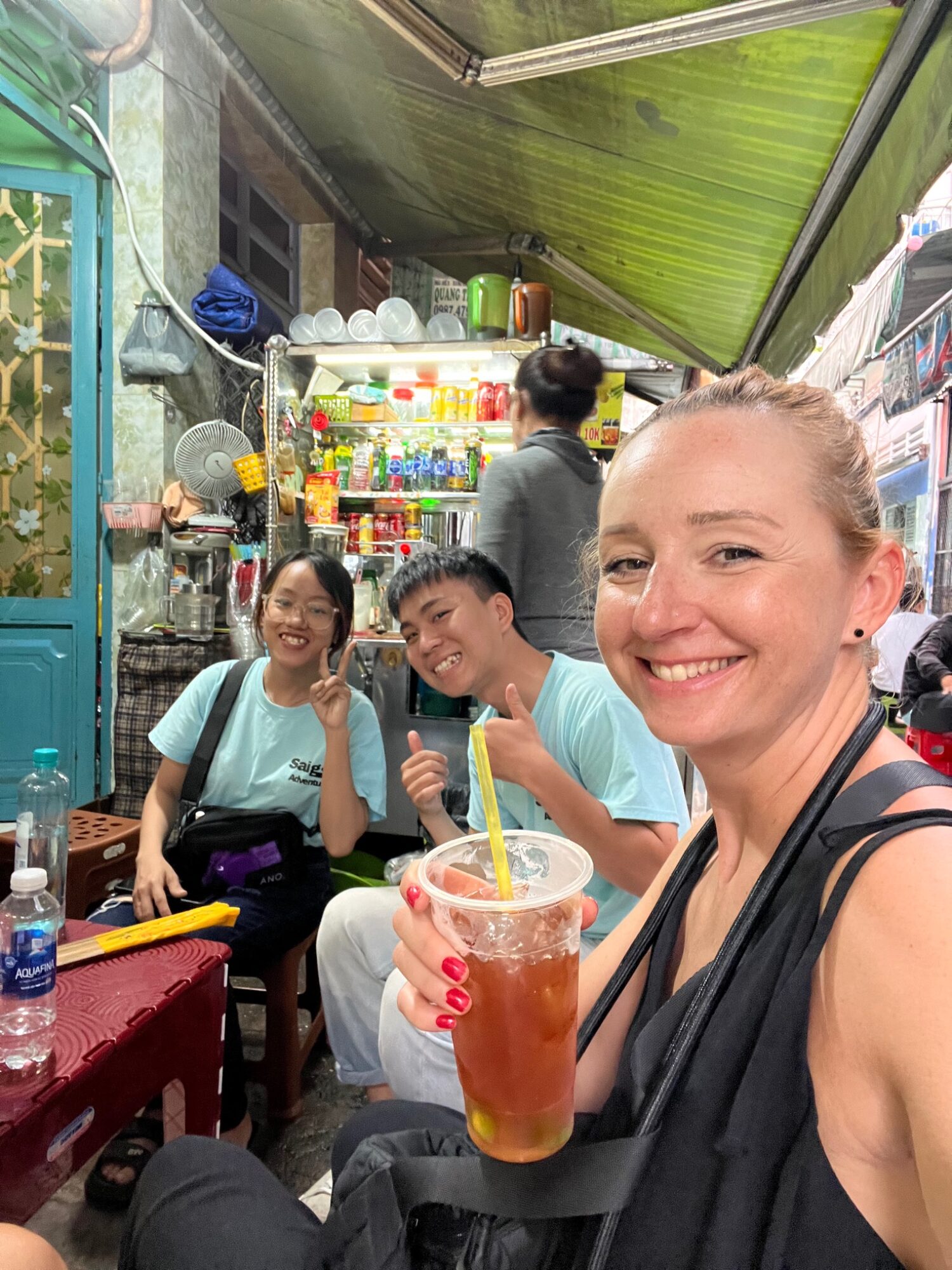 Andreja smiling with a drink and the scooter tour group at a local market
