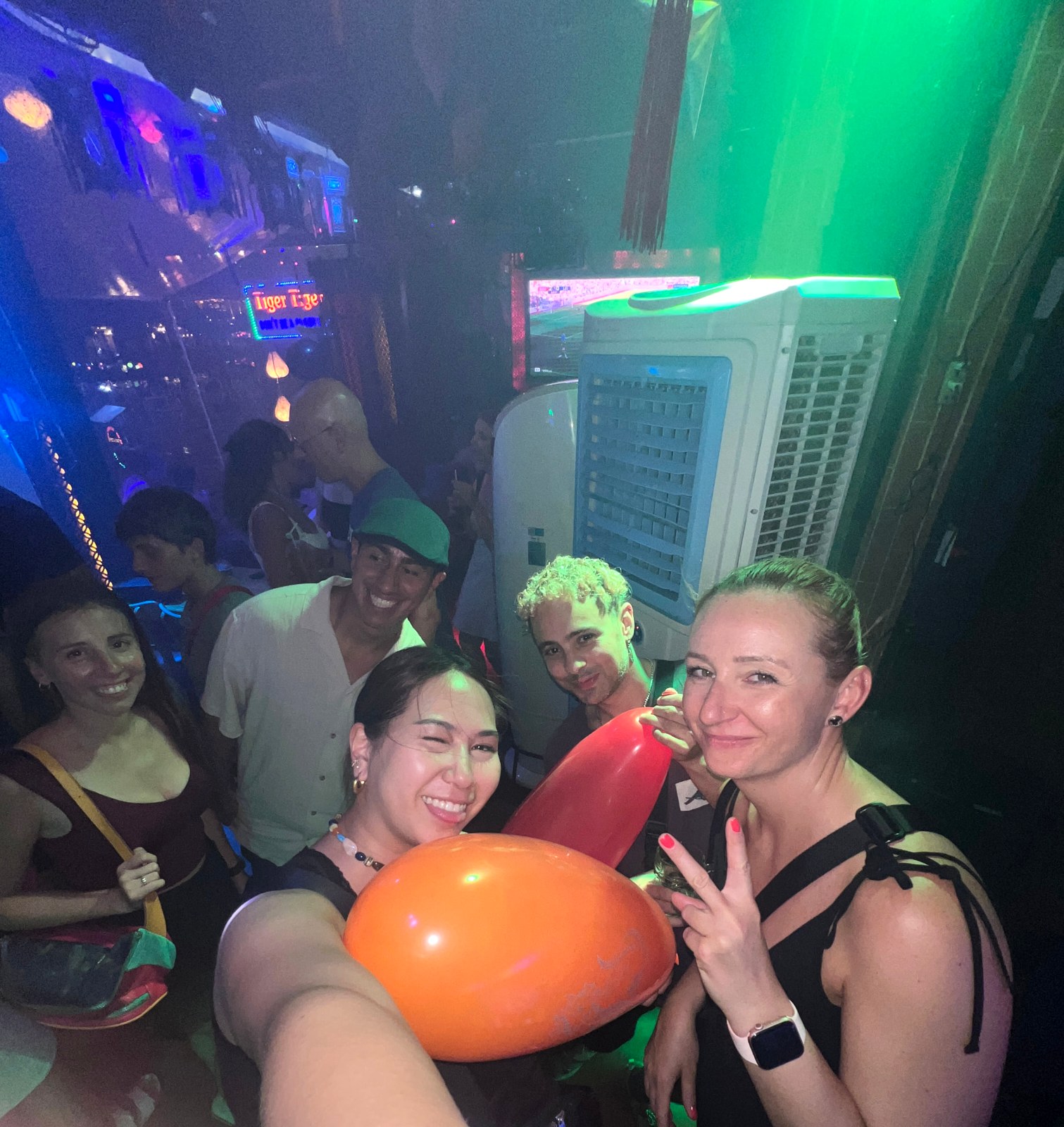 Andreja and friends with balloons in a packed, neon-lit Tiger bar in Hoi An