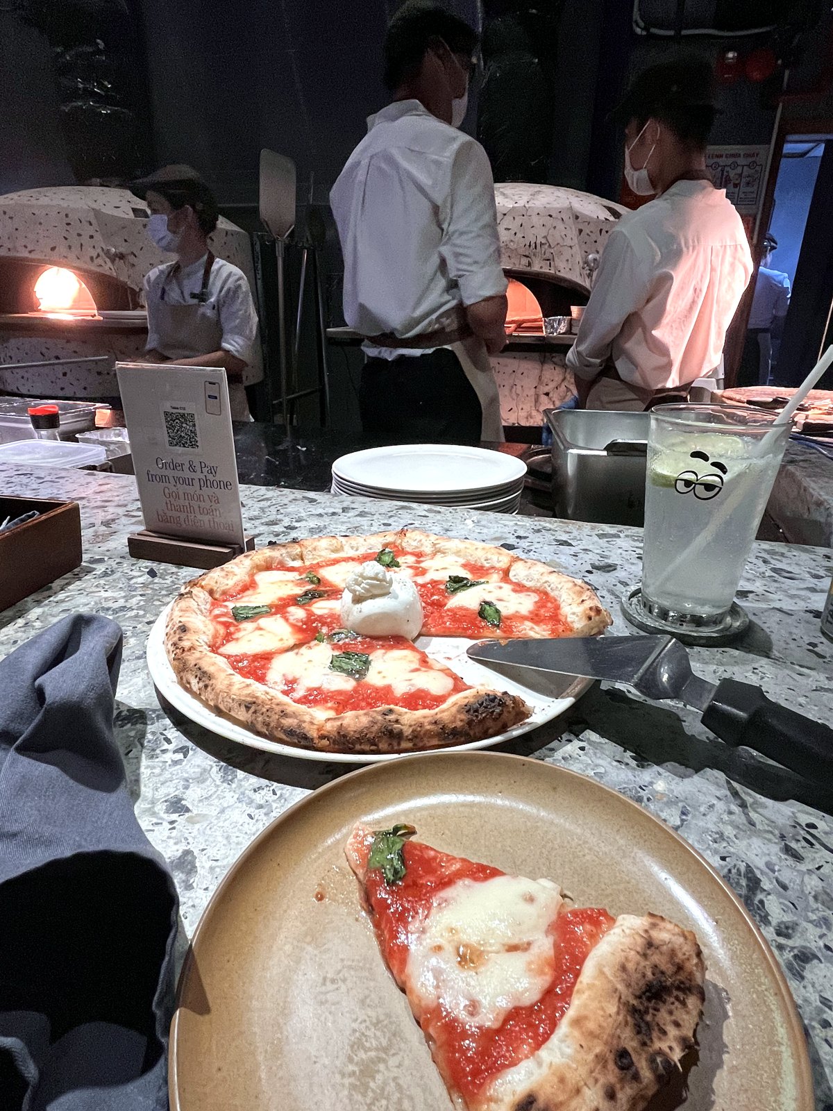 Margherita pizza with burrata and a slice on a plate at Pizza 4P's, chefs by the wood-fired oven
