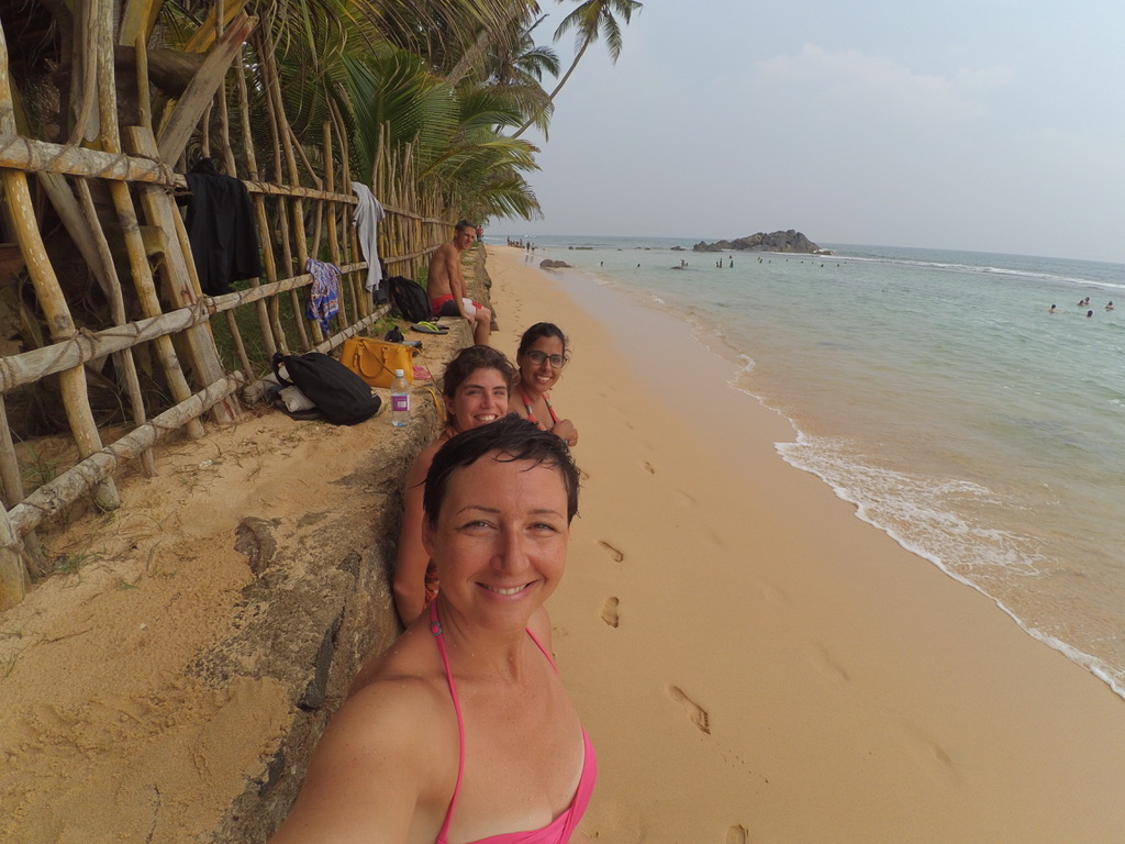 Four travellers who met that morning smiling for a selfie on a palm-lined beach in Sri Lanka