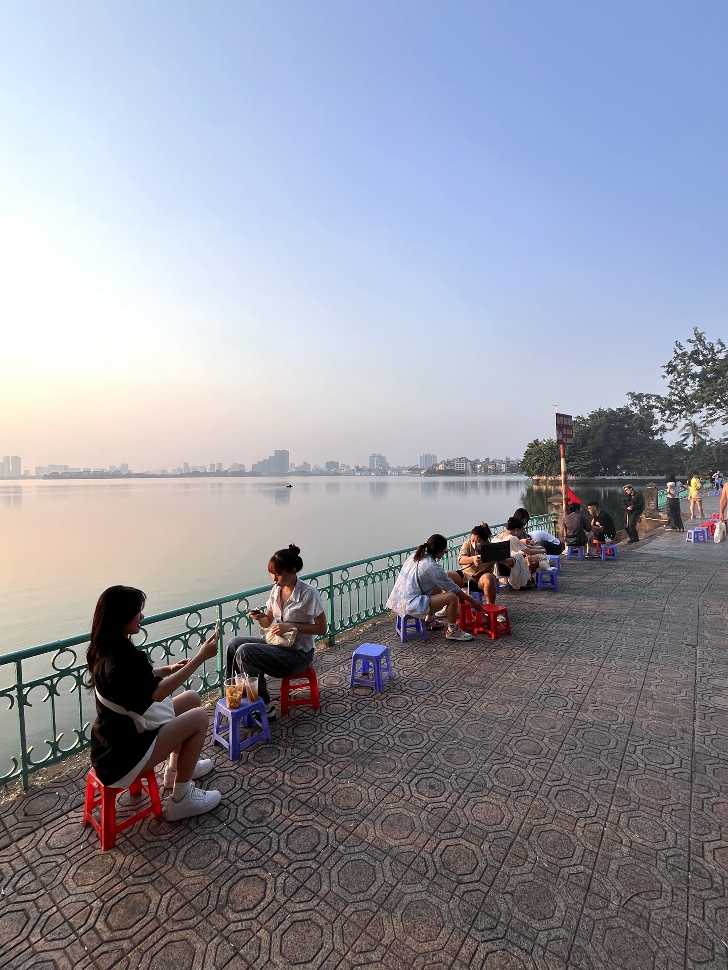 Sunset over Hanoi's West Lake seen from small plastic street stools
