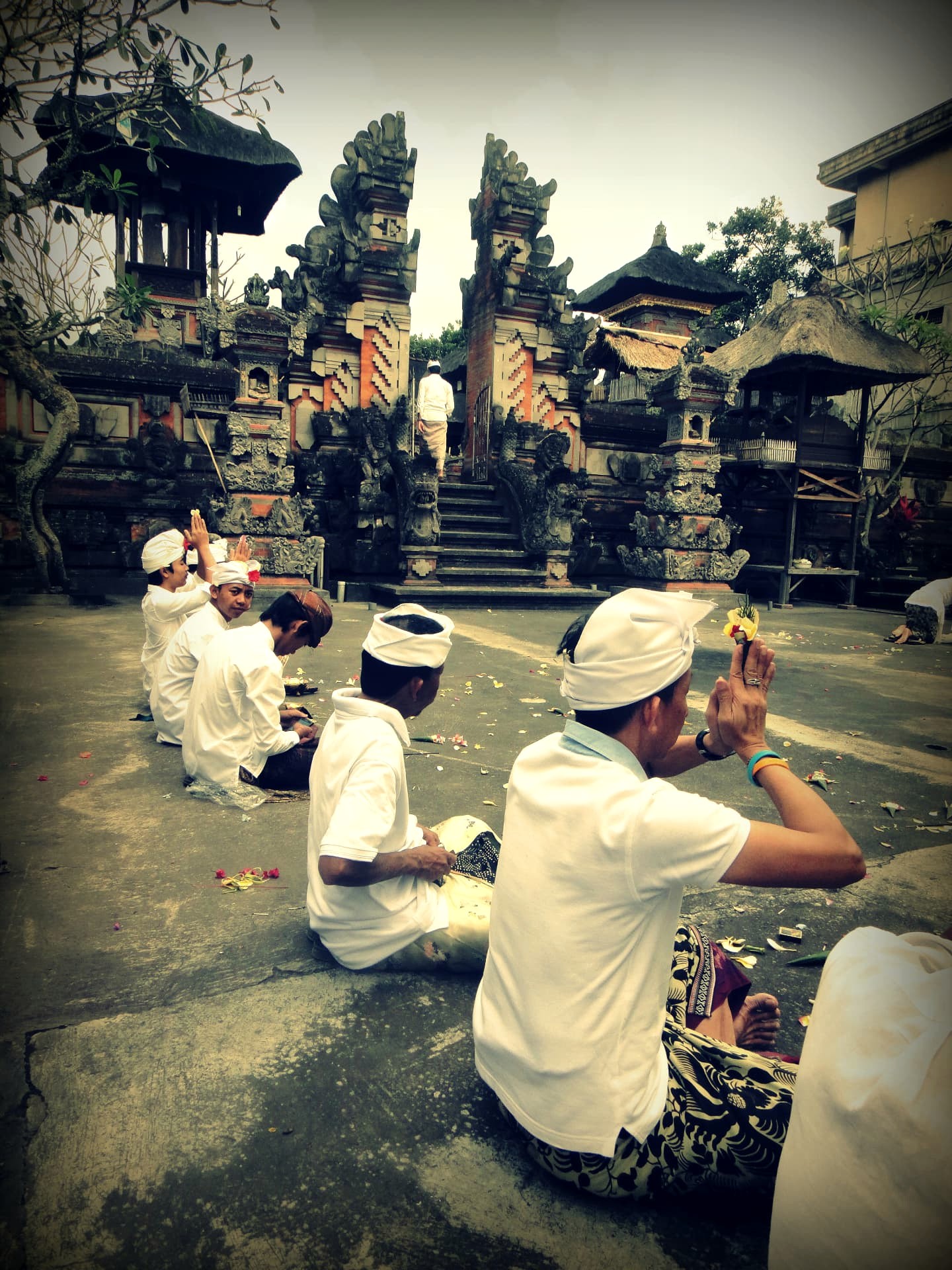 Men dressed in white praying at a Balinese temple gate
