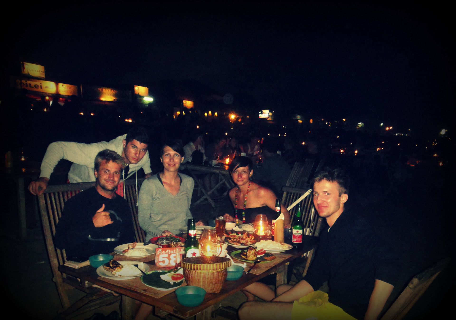 A group of travellers around a table of grilled seafood and rice at Jimbaran beach