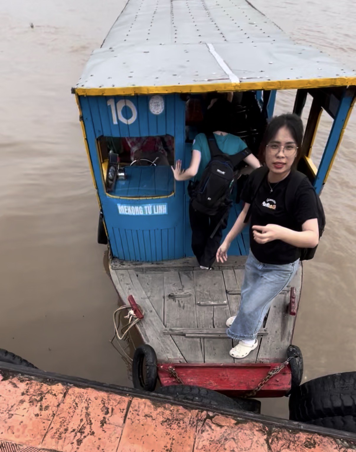 Our tour guide stepping onto the blue wooden boat on the Mekong Delta