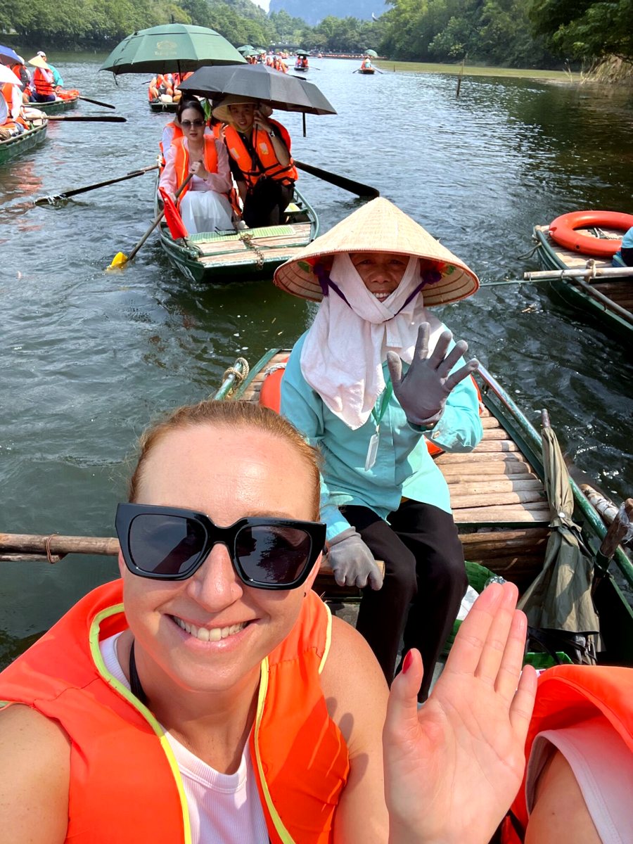 Smiling Vietnamese lady in a conical hat rowing the boat in Tràng An, Ninh Binh