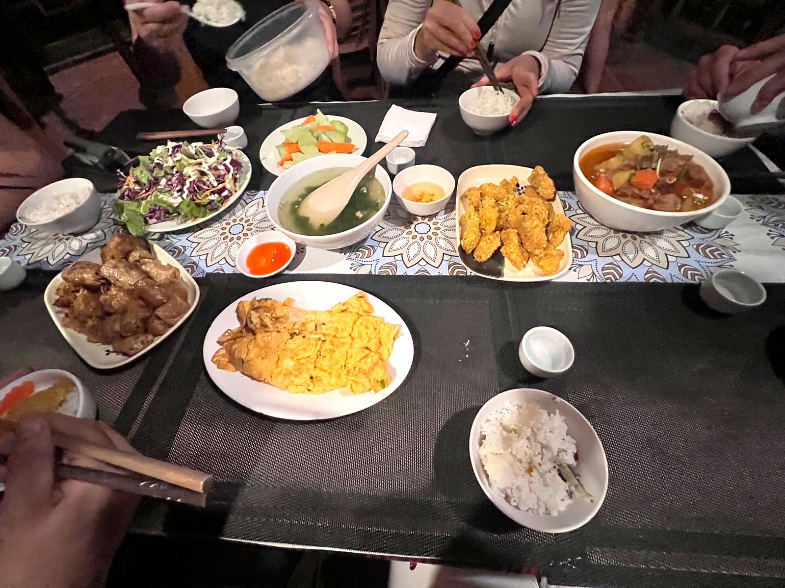 Shared dinner dishes, rice and small cups on the evening table