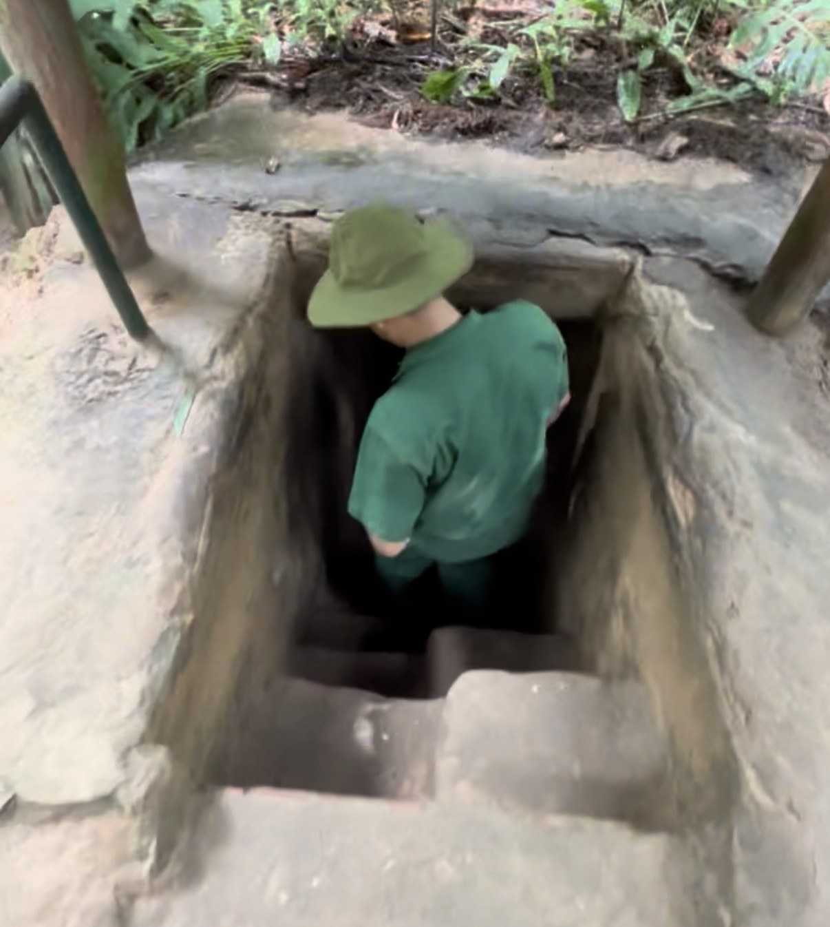 Traveller following a local guide down the narrow stairs into a Cu Chi tunnel