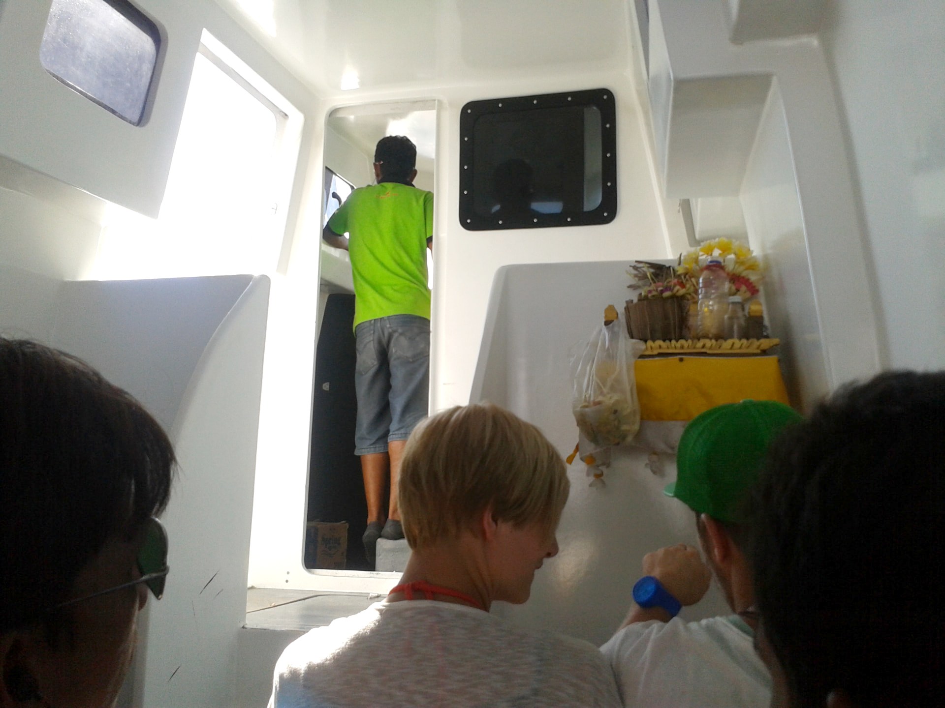 Inside the cabin of a speedboat to the Gili Islands with passengers and a small Balinese offering shrine