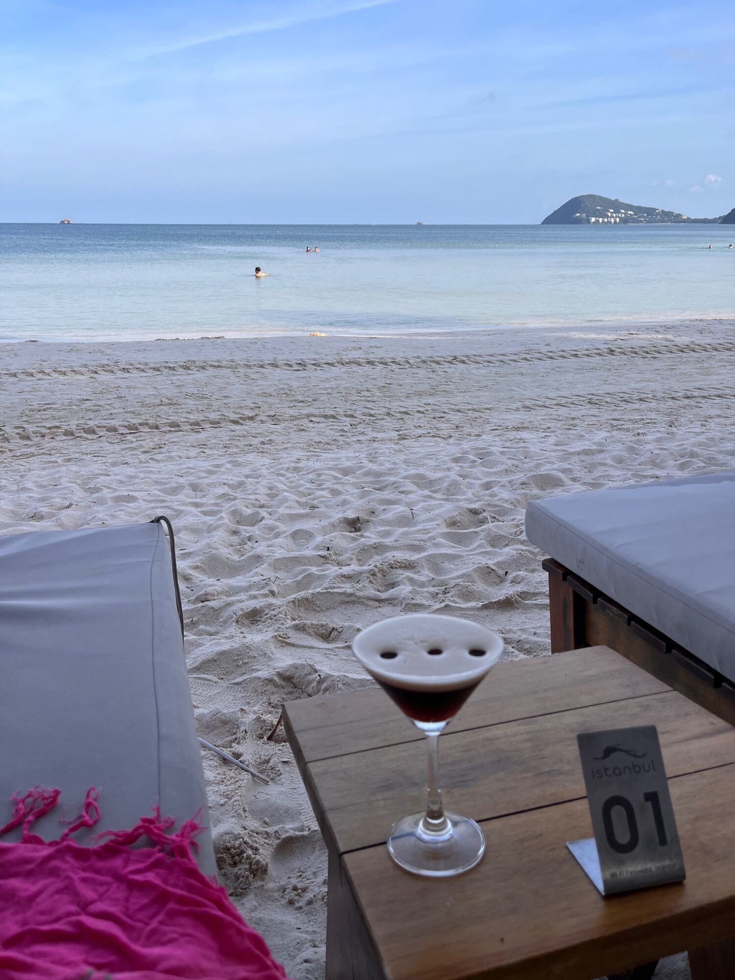 Espresso martini beside an Istanbul Beach Club table marker numbered 01, with Sao Beach beyond