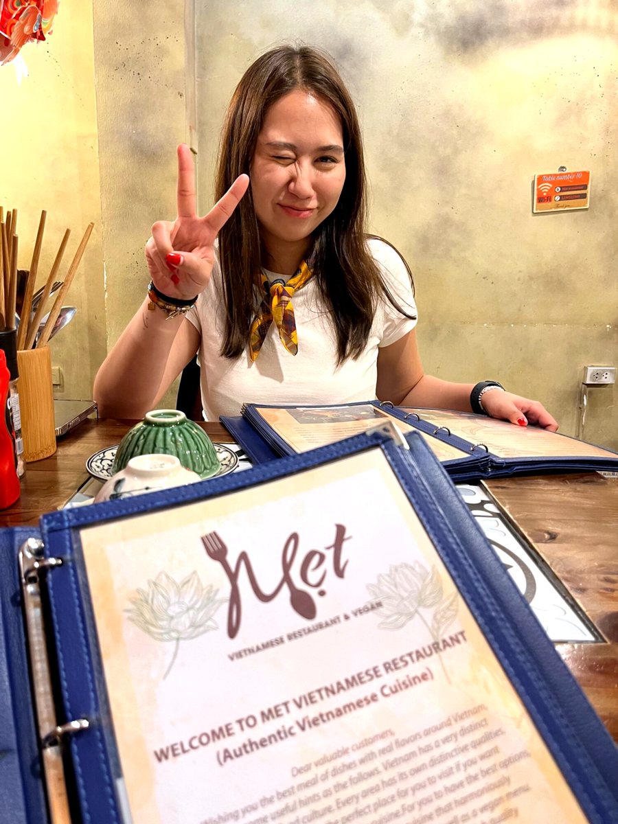 A friend smiling behind a restaurant menu in Hanoi
