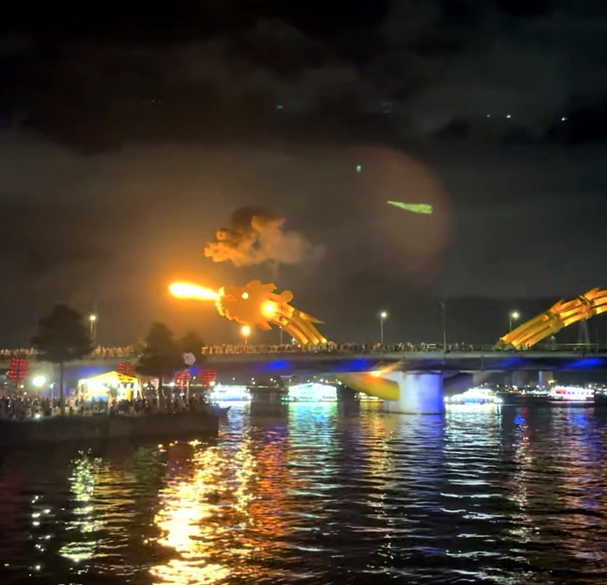 Da Nang's Dragon Bridge breathing fire at night above colourful reflections on the river