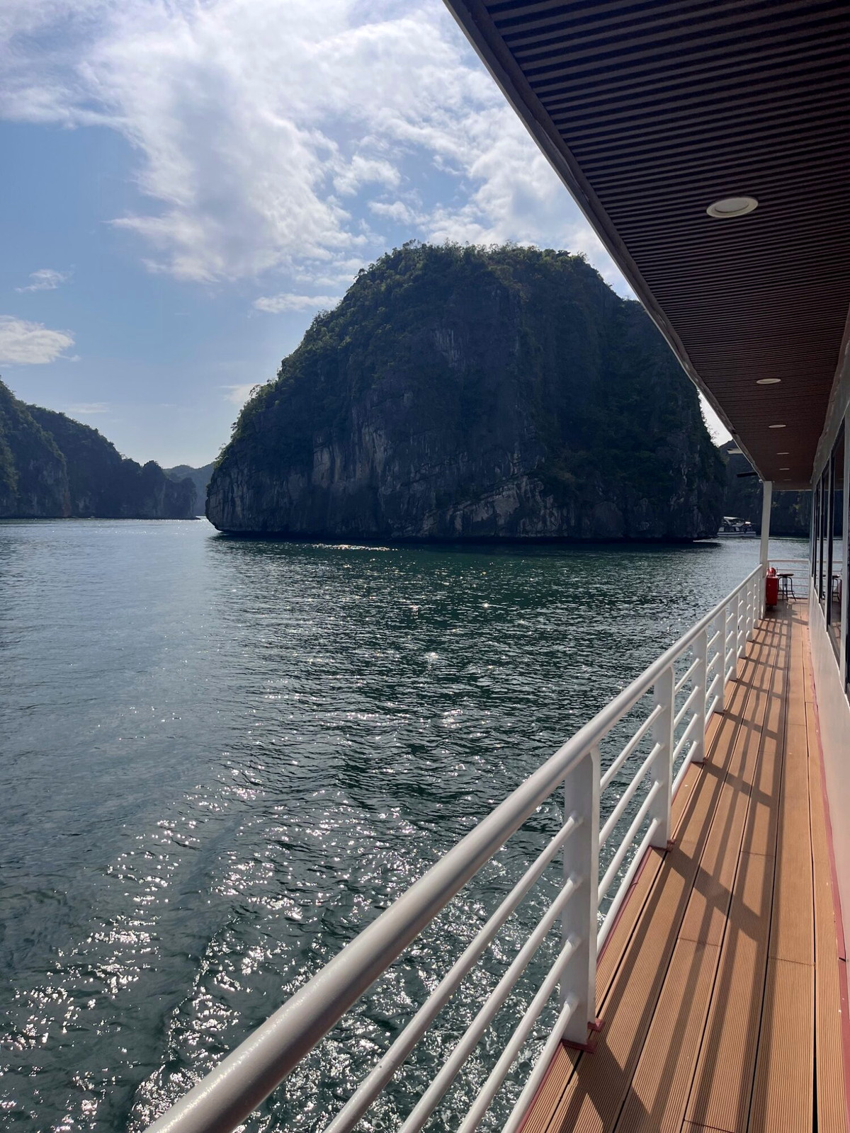 Wooden cruise boat deck beside limestone cliffs in Lan Ha Bay