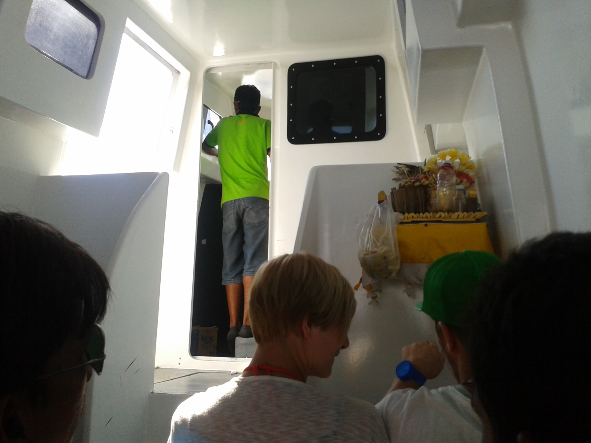 Inside the cabin of a speedboat to the Gili Islands with passengers and a small Balinese offering shrine