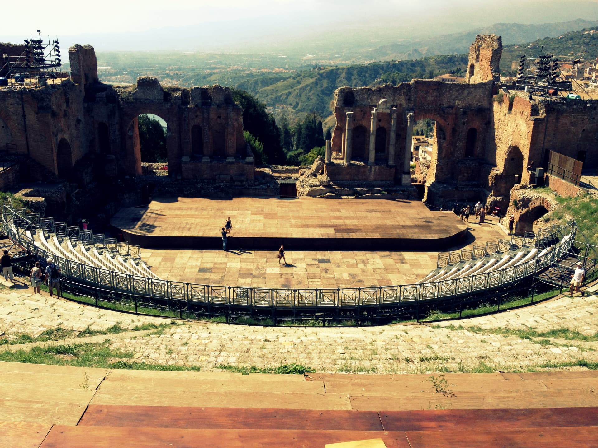 The ancient Greek Theatre of Taormina seen from above with the coastline behind it