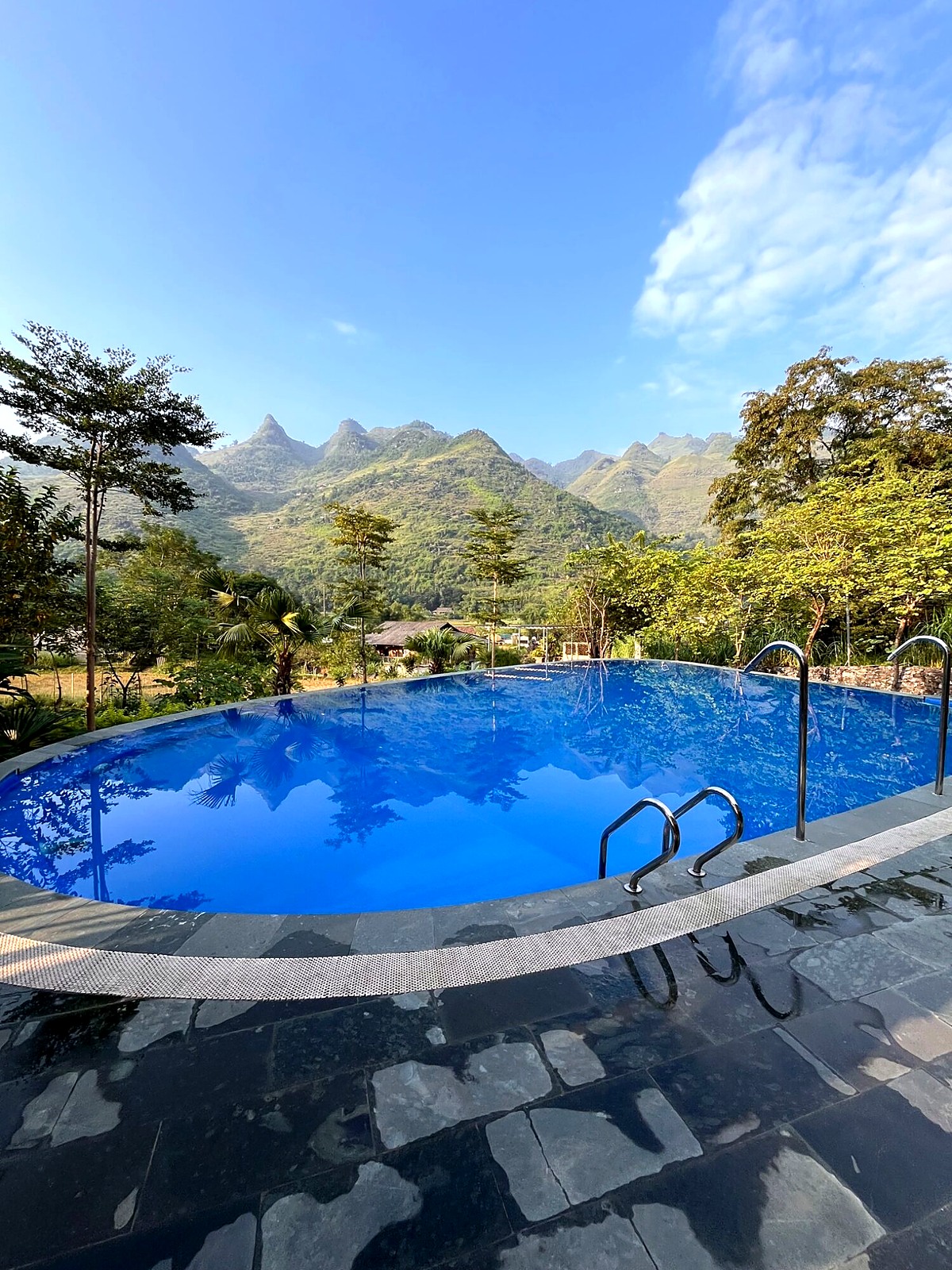 A blue swimming pool surrounded by mountain scenery at the first overnight stop