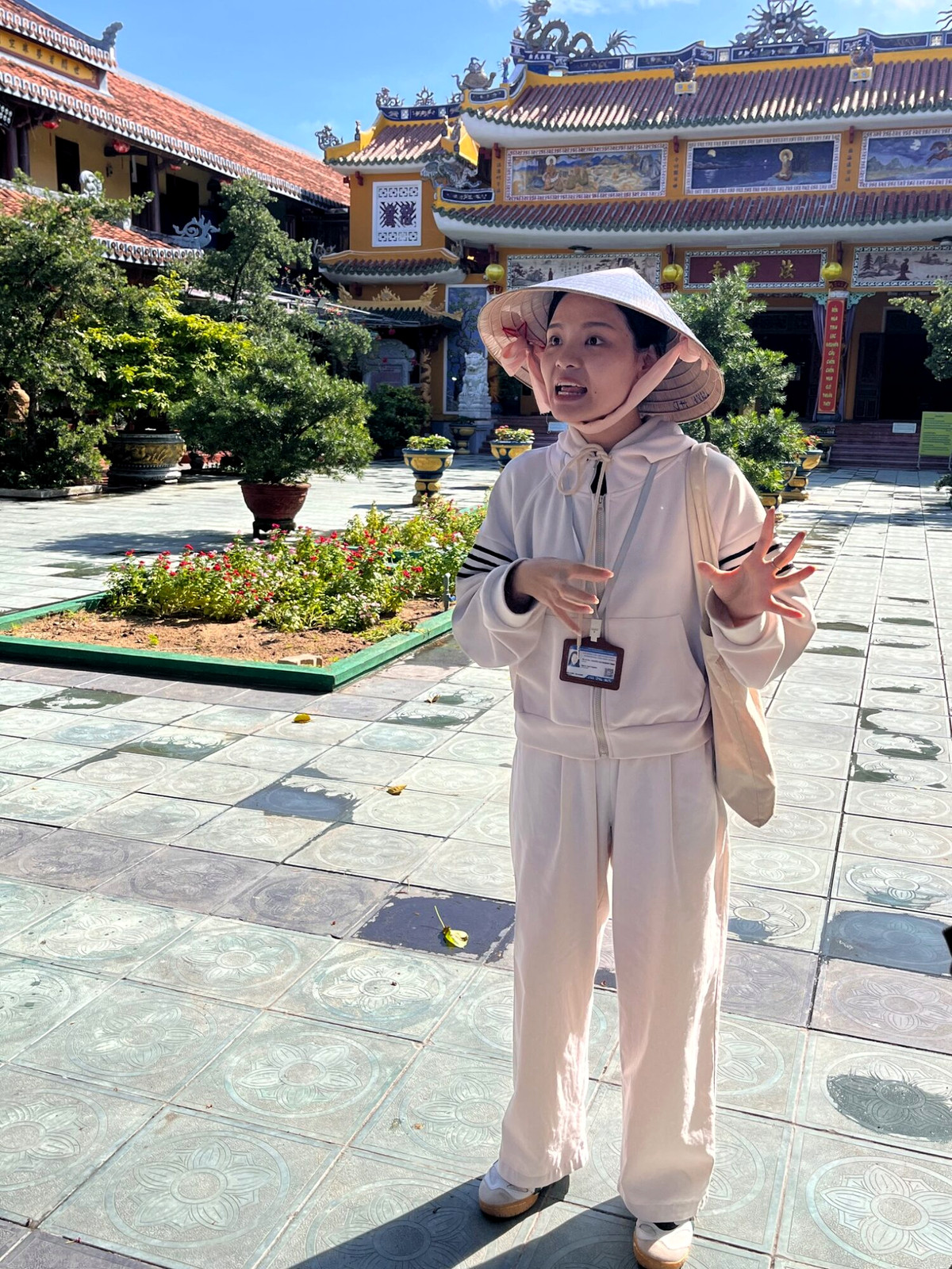 Walking tour guide in a sun hat in a historic Hoi An courtyard