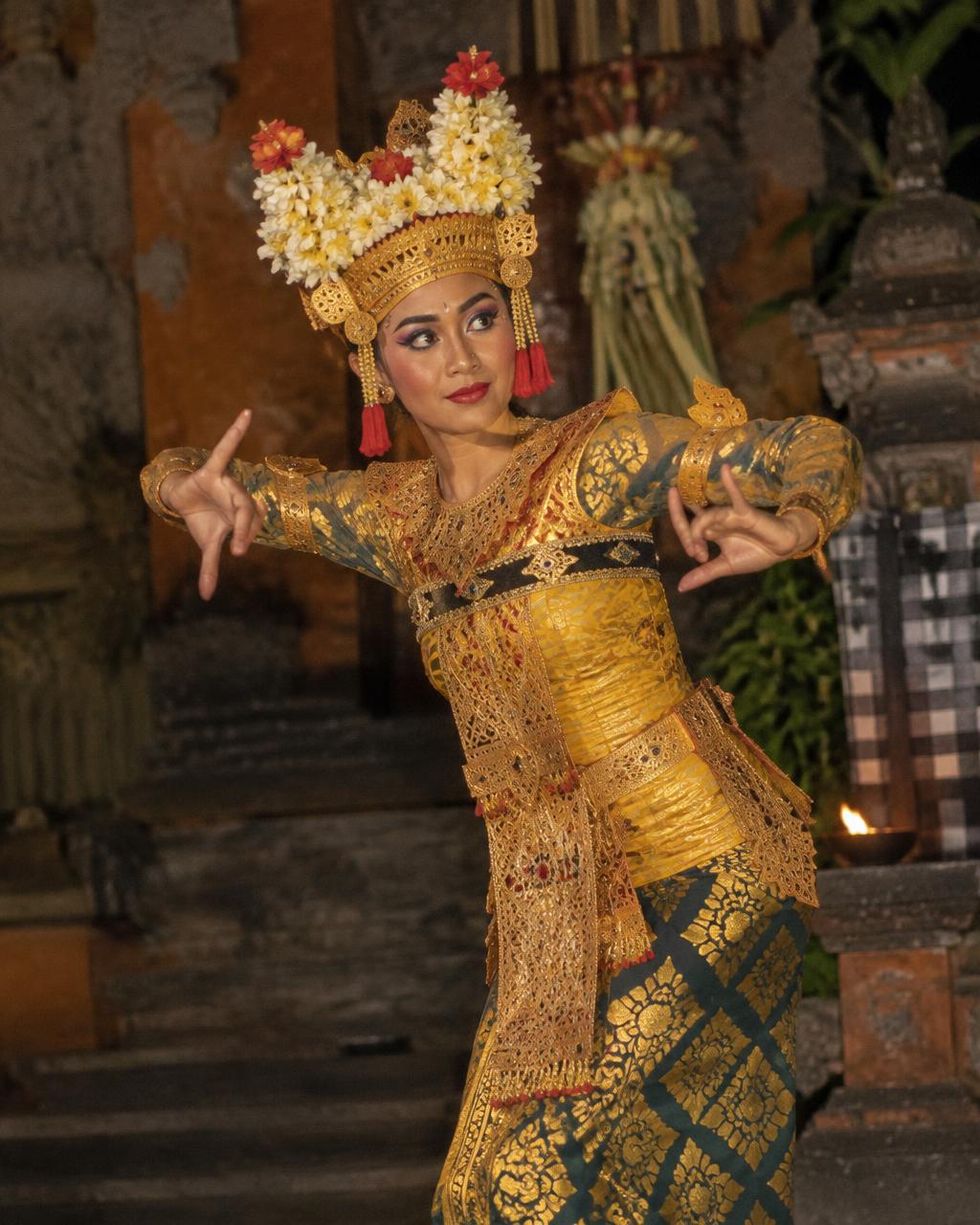 A Balinese Legong dancer in traditional gold costume performing at night